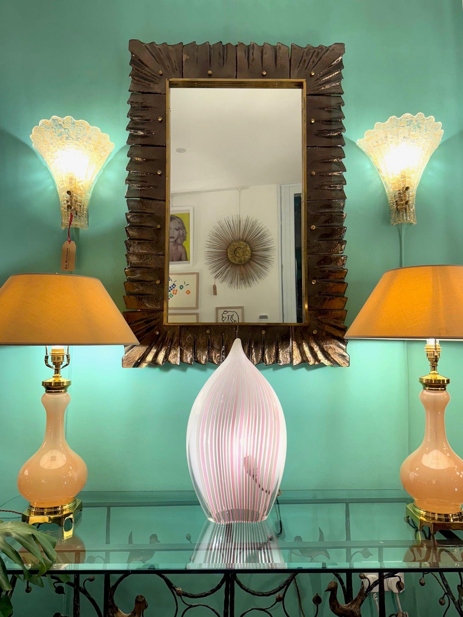 Uno splendido specchio italiano in bronzo con cornice in vetro di Murano, con cornice interna in ottone e borchie in ottone. La cornice è composta da 16 sezioni in vetro di Murano color bronzo, fissate con borchie sagomate in ottone massiccio