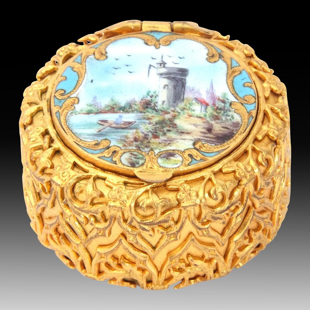 This is a beautiful antique French ormolu and enamel patch box that dates back to between 1840-1850.

The circular sides and bottom of the box are embossed with rich gold ormolu arabesque leaf and enriched scroll cast filigree trellis work. The