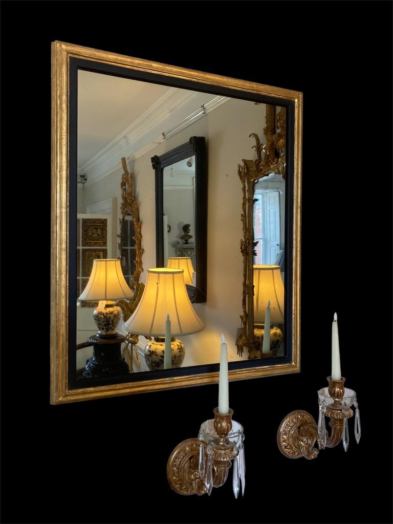 An exquisite matching pair of giltwood mirrors with a black inlay that accentuates the 19th Century mirror plate and the later gilt frame.