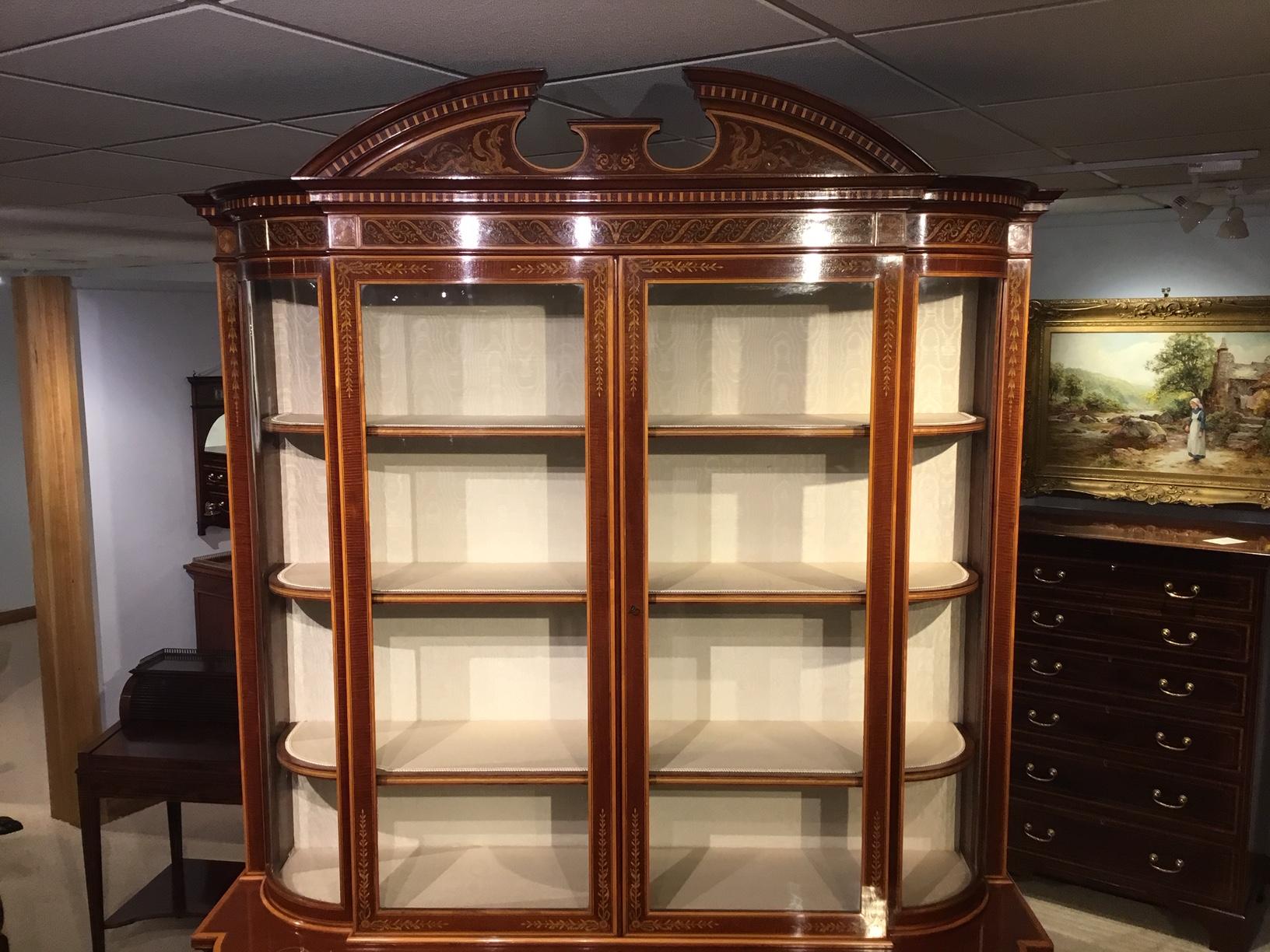 A stunning quality marquetry inlaid cabinet by Edwards & Roberts of London. The upper section with a broken swan neck pediment and marquetry inlaid attendant griffins above a ribbon and swag inlaid frieze. The fiddle back mahogany central