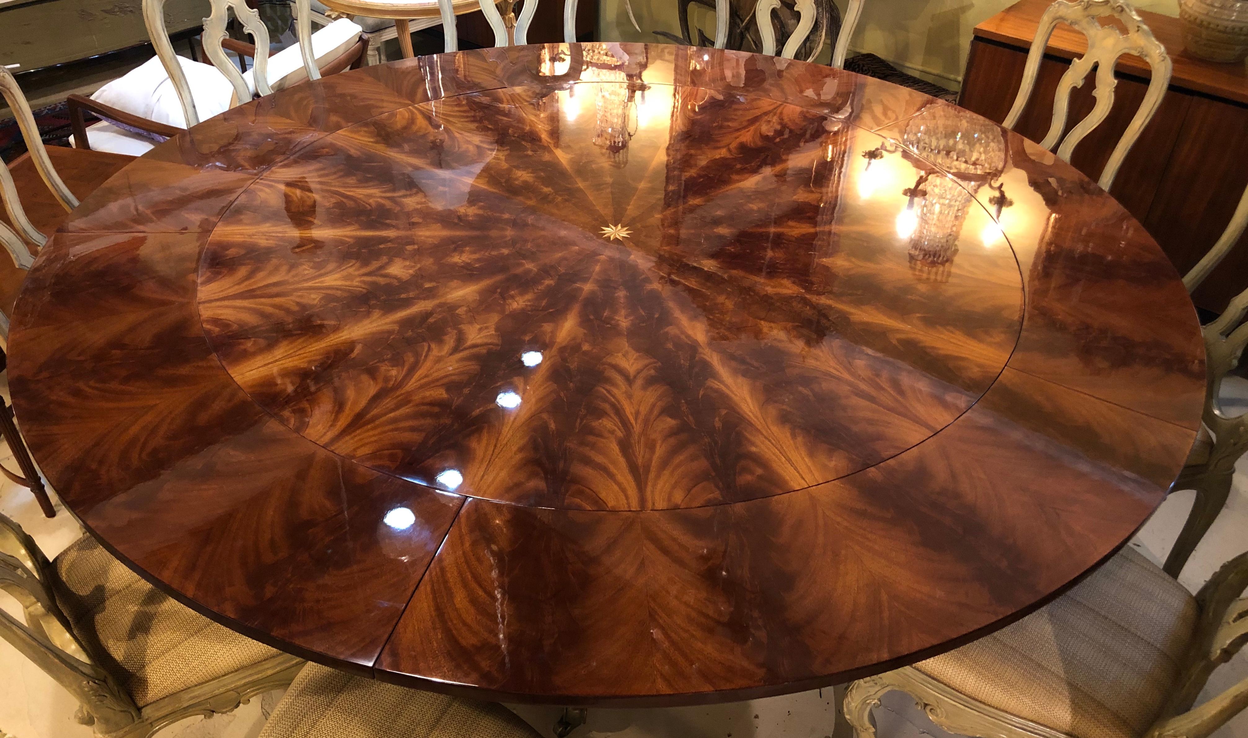 A  Georgian style flame mahogany sunburst inlaid circular dining table with five twelve inch leaves. Fully extended with all leaves this spectacular table is 87.5 inches in size. The strong and study table base having quad sprayed legs with brass