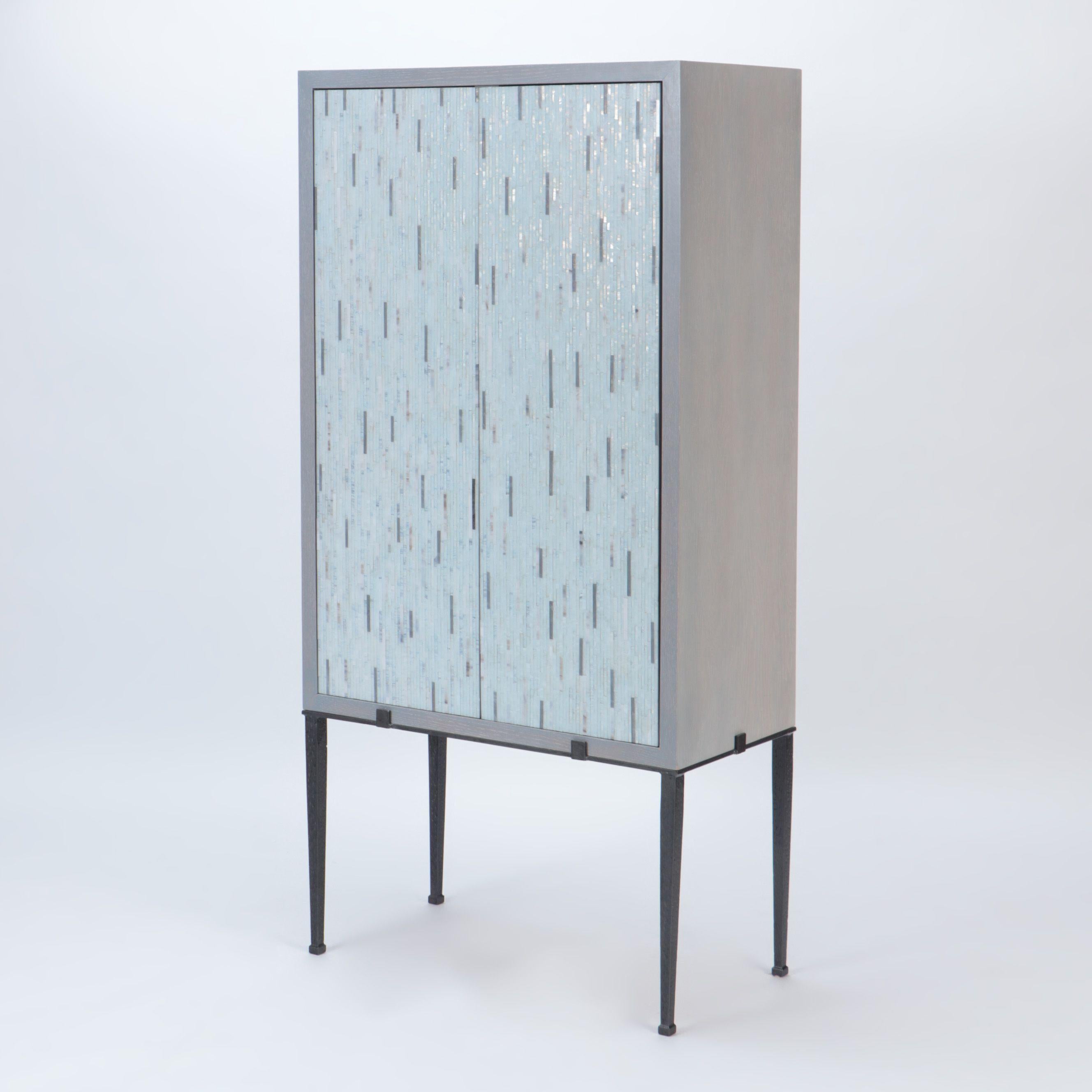 Ein stilvoller maßgefertigter Schrank aus gebrannter Eiche mit Glasmosaik.
Türen und ruht auf einem schwarz lackierten Stahlrahmen.