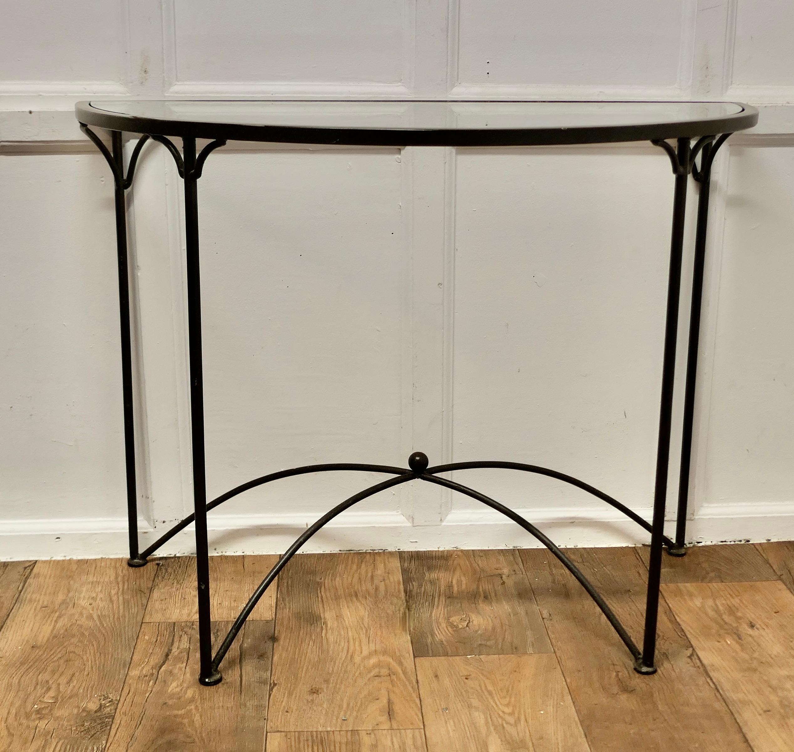 A Stylish Iron and Glass Console Table 

 This is a lovely table it has been designed in the French mid century Style, the base is forged in wrought iron, it has crossing arched curved stretchers, the thick glass top is bevelled all around in a half