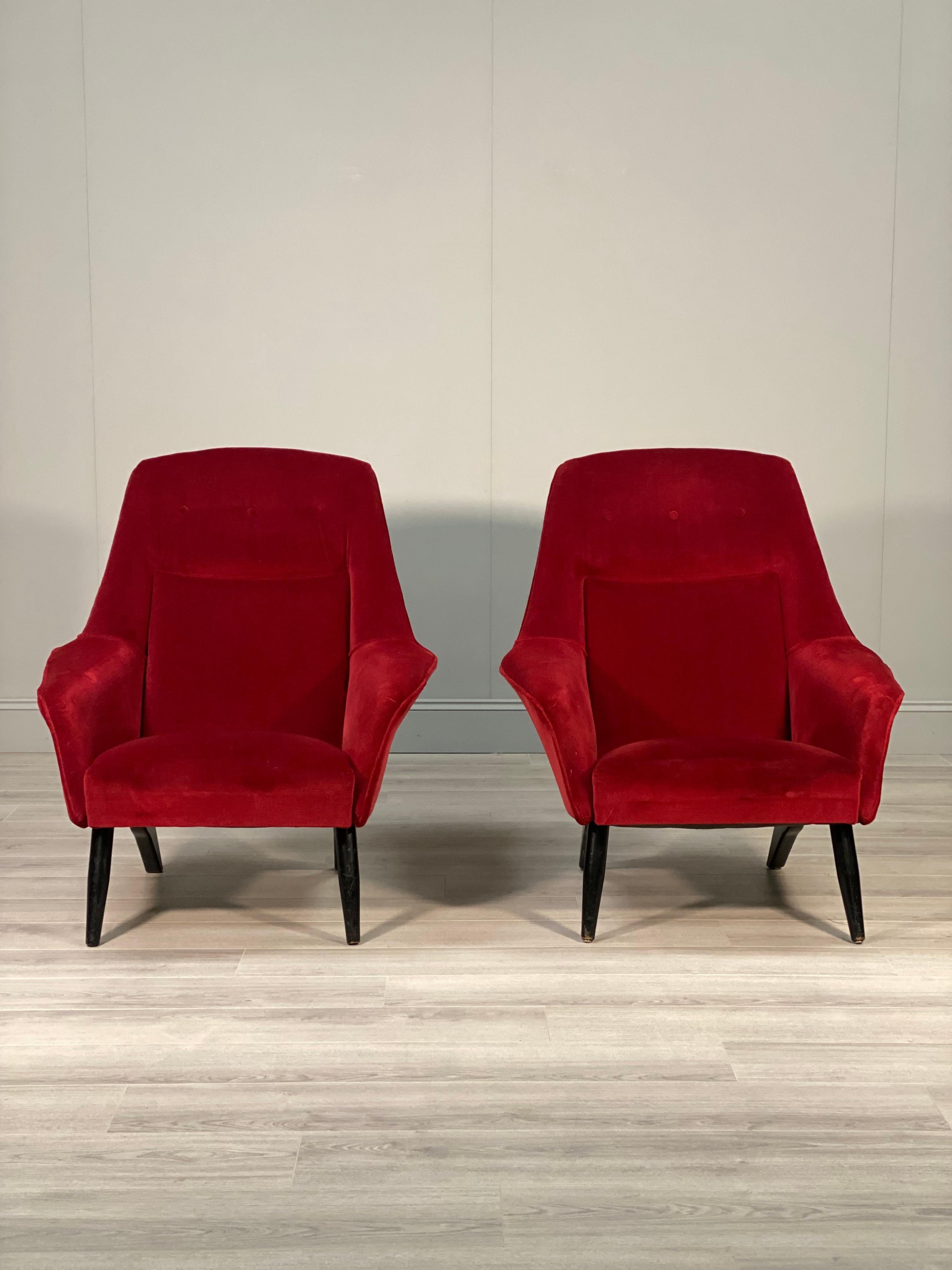 A stylish pair of armchair’s dating to the 1960’s. The armchairs have a stylish mid 20th century shape with a high back and winged armrests sitting on stylish ebonised legs. The chairs are in very good original condition with the original rich red