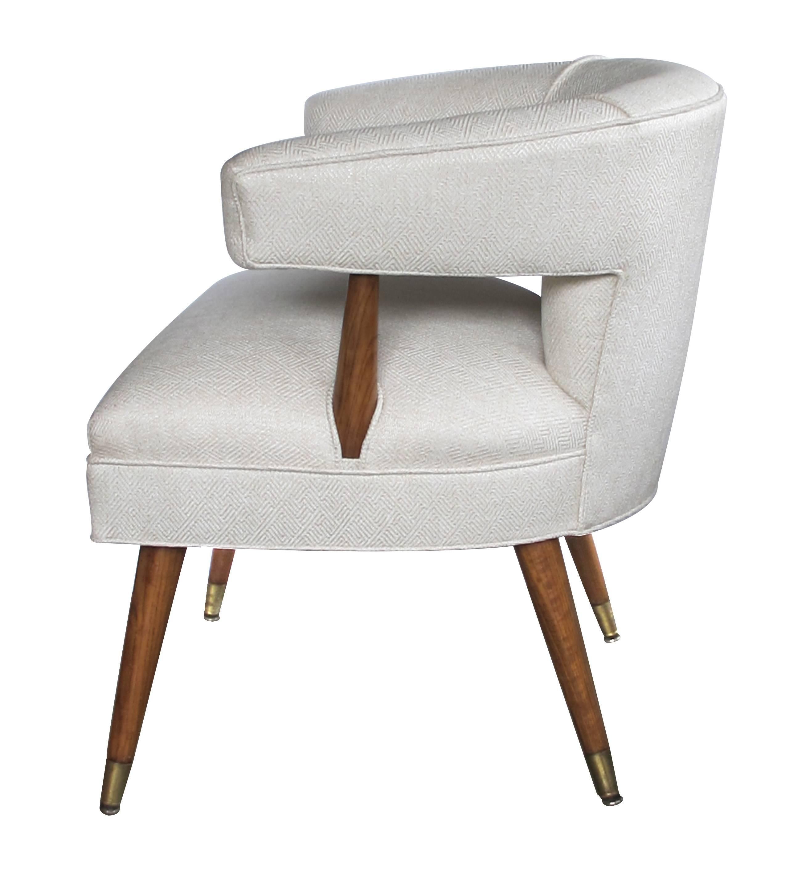 Each with sculptural profile and incurved back upholstered back over a tight seat; raised on splayed supports with brass sabots.