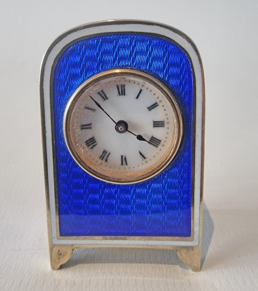 A very pretty silver gilt and blue guilloche enamel sub miniature carriage or boudoir clock in carry case.  The case, of arched form, the superb engine turned blue guilloche enamel surrounded by a white enamel border. The white enamel dial with
