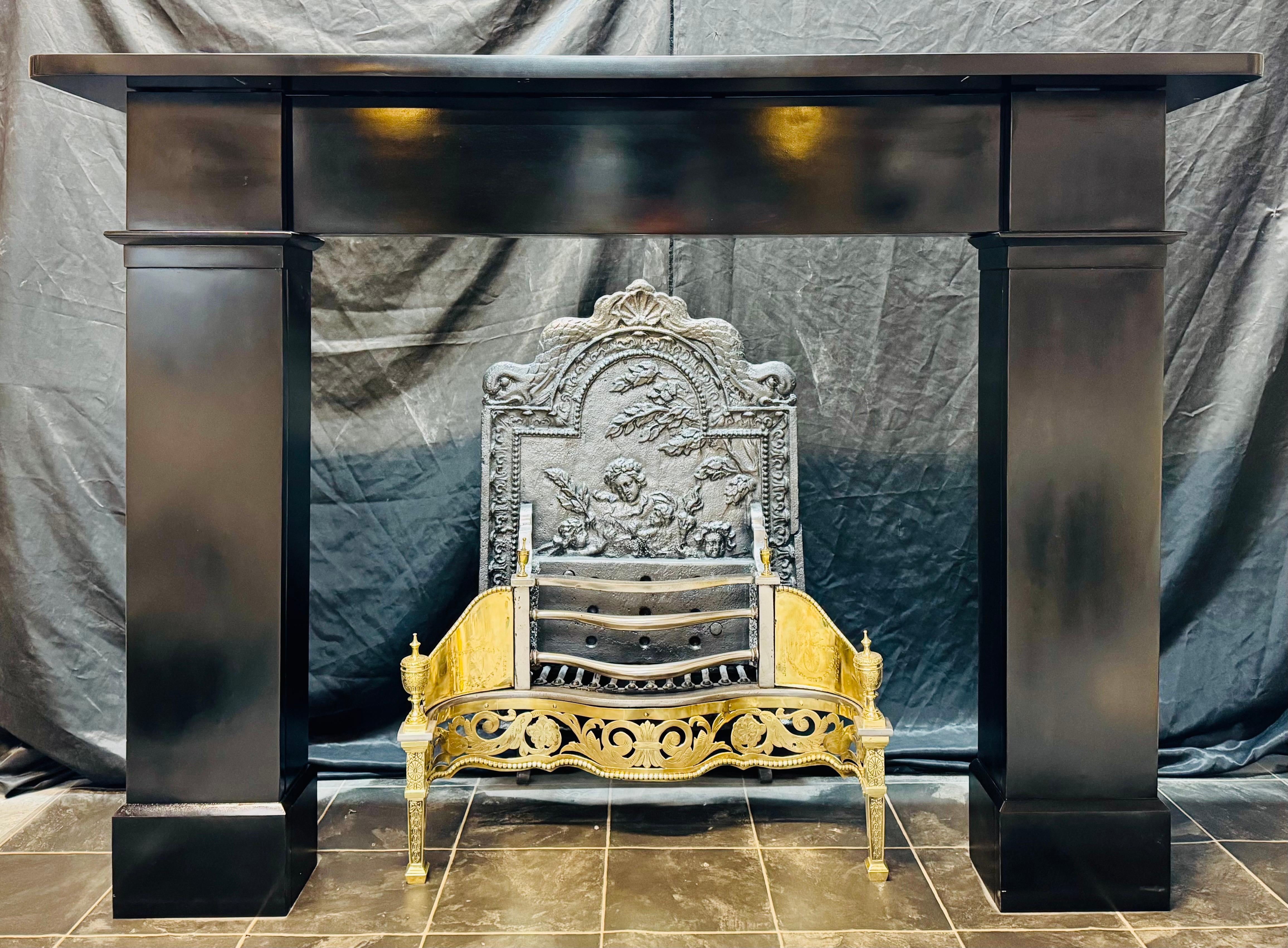 A masculine 19th Century Victorian Scottish Slate fireplace surround. 
A deep unadorned top shelf with rounded corners sits above a plain frieze. This is flanked in turn by a pair of wide sturdy jambs (legs) with block and capping intersections to