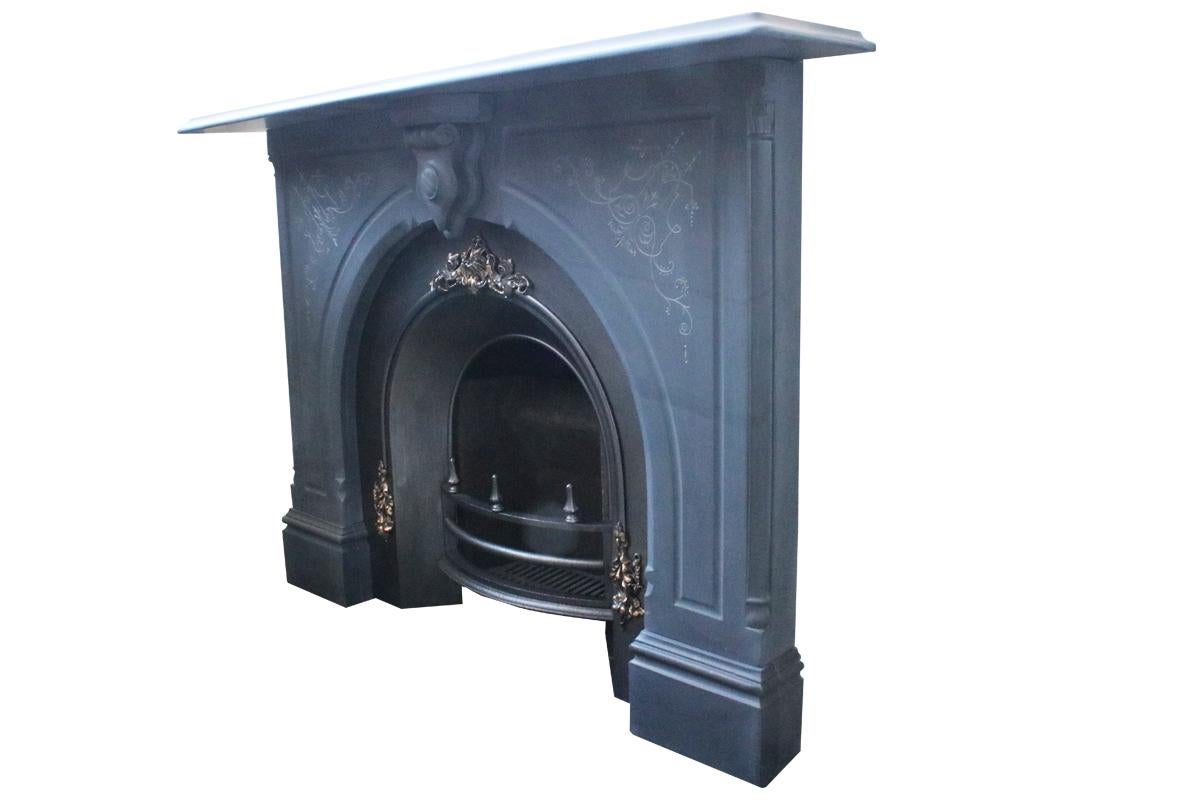 A substantial mid Victorian carved slate fire surround with fine etched detail to the spandrels, quarter columns with carved capitals to the outside returns and an unusual heavily carved keystone, circa 1860.

Pictured with an original arched