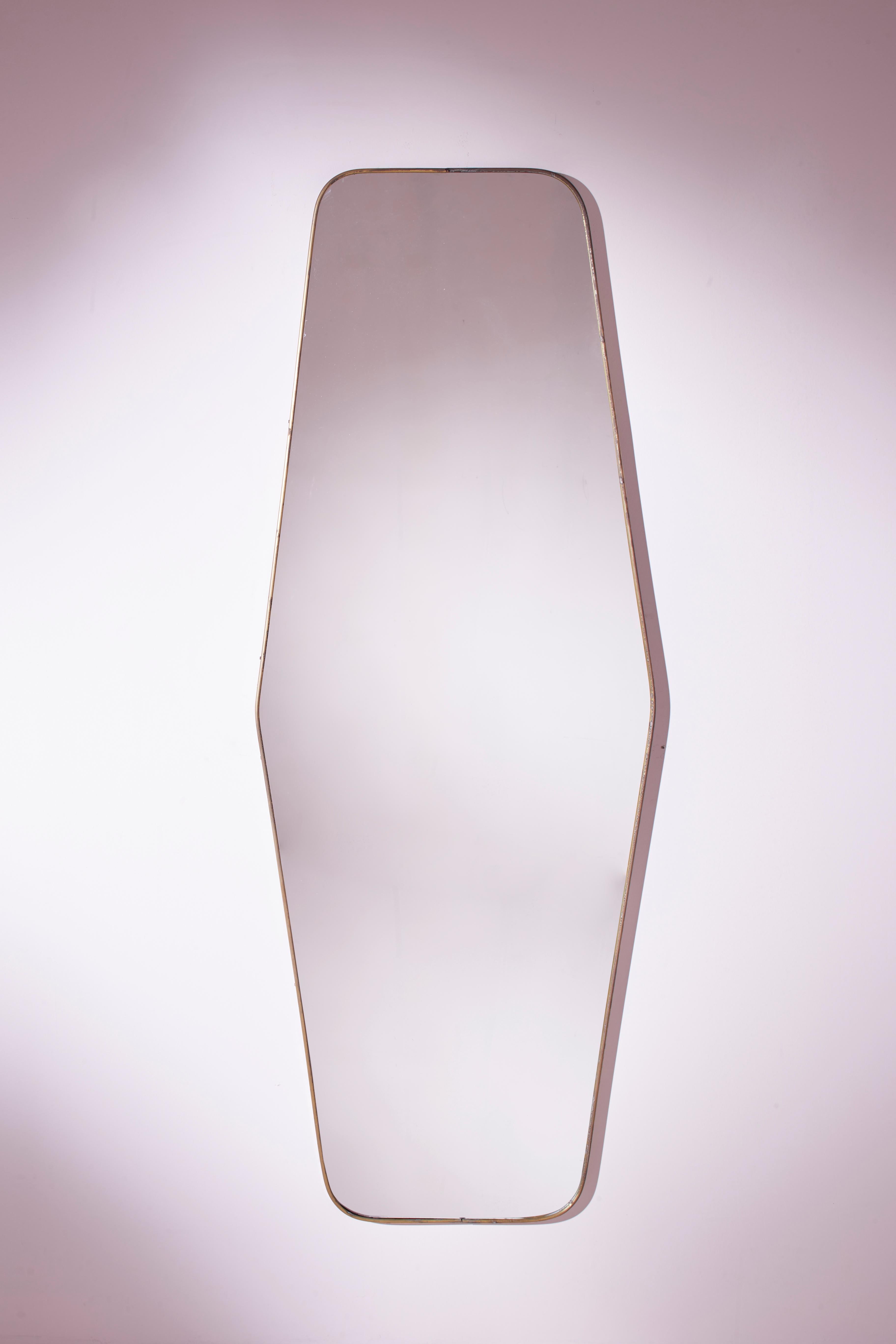 An impressive Italian brass wall mirror from the 1950s boasting an elegant elongated hexagonal shape.

This remarkable full-length mirror comprises an original plate from the 1950s, elevated by an light and modernist brass frame, making it a