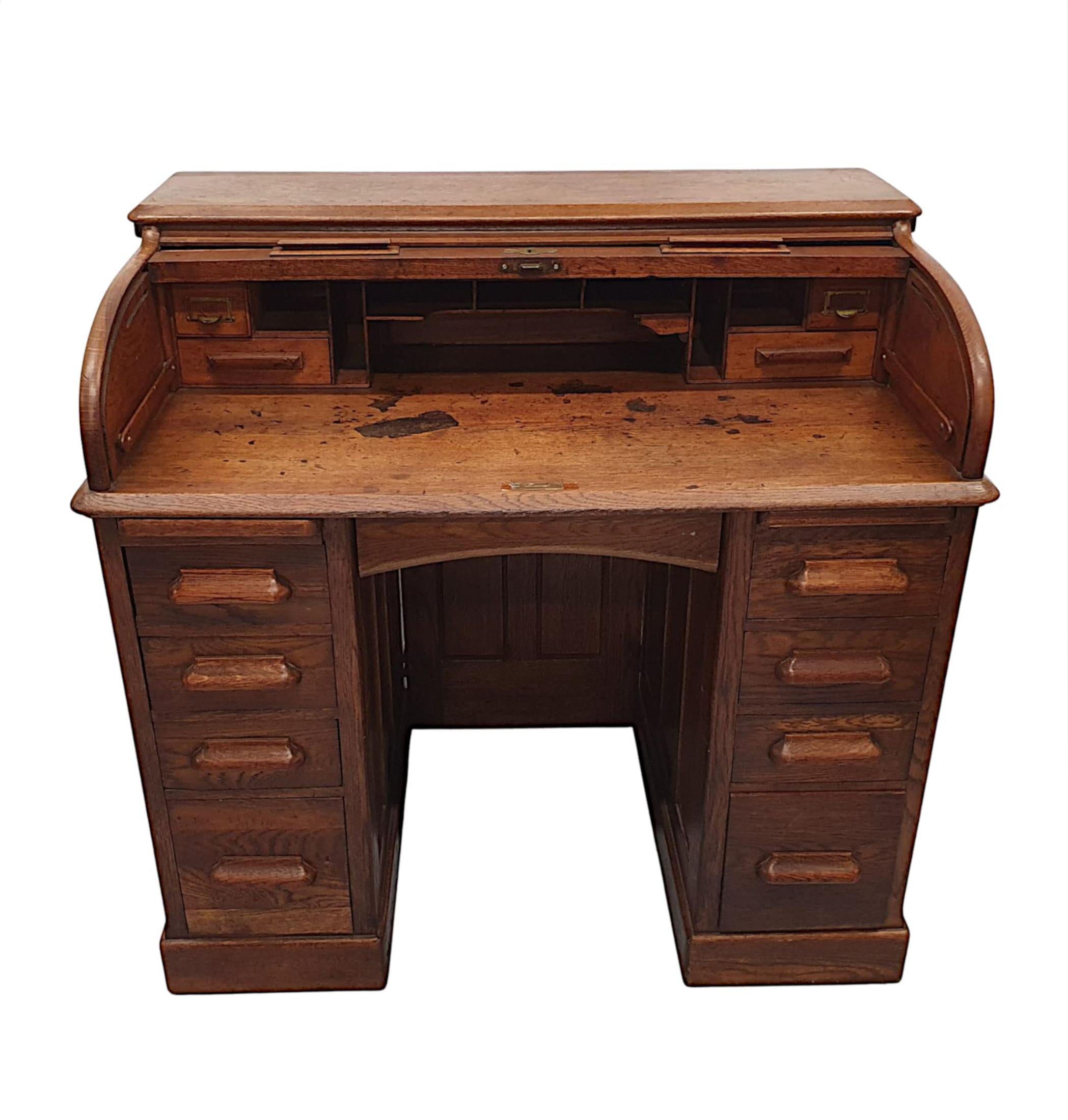 A superb 1920s beautifully patinated oak roll top desk of neat proportions, finely carved and of gorgeous quality. The moulded top of rectangular form raised over D-shaped tambour slatted front with decorative brass escutcheon and moulded pulls. The
