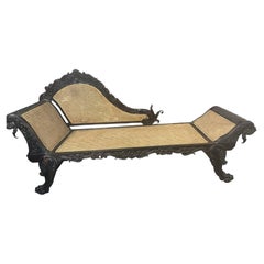 A superb Asian carved padouk wood chaise, caned seat and back, 19th c