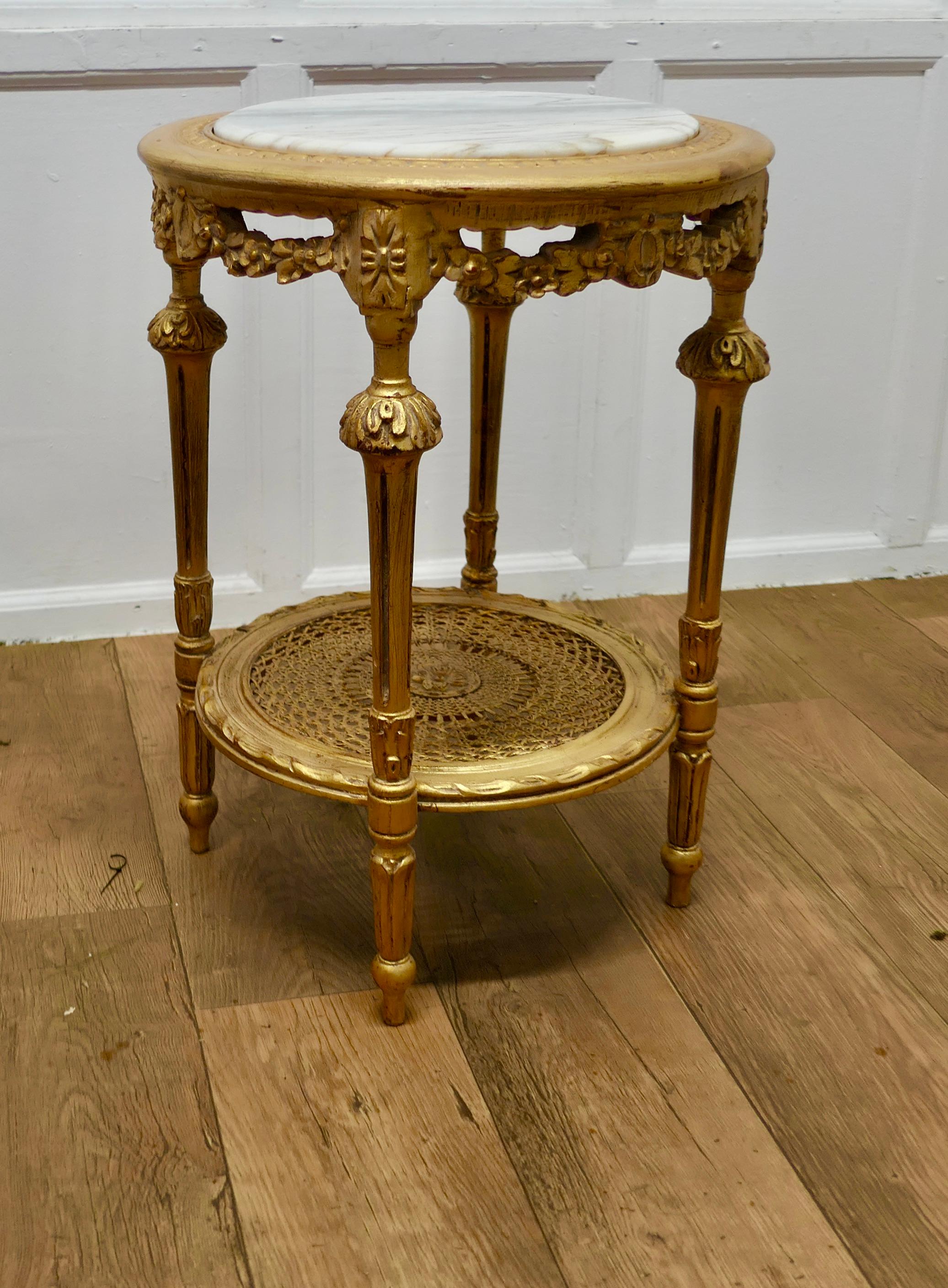 A Superb French 19th Century Gilt Salon Table

A superb French gilt round lamp or side table which has a marble top and and a bergère undertier 
The table is in very good condition and would work almost anywhere 
Table is 28” high and 20” in