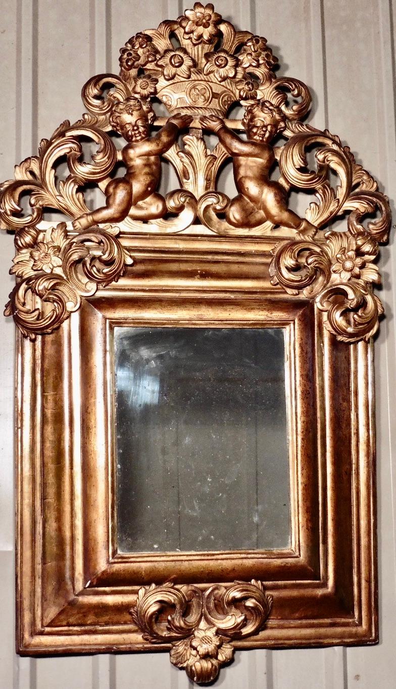 A superb large early 19th century carved gilt mirror

 This is the most impressive large carved gilt mirror, the glass is set in a deep moulded frame which is crowned with exquisite carvings of cherubs holding a basket of flowers, the flower theme
