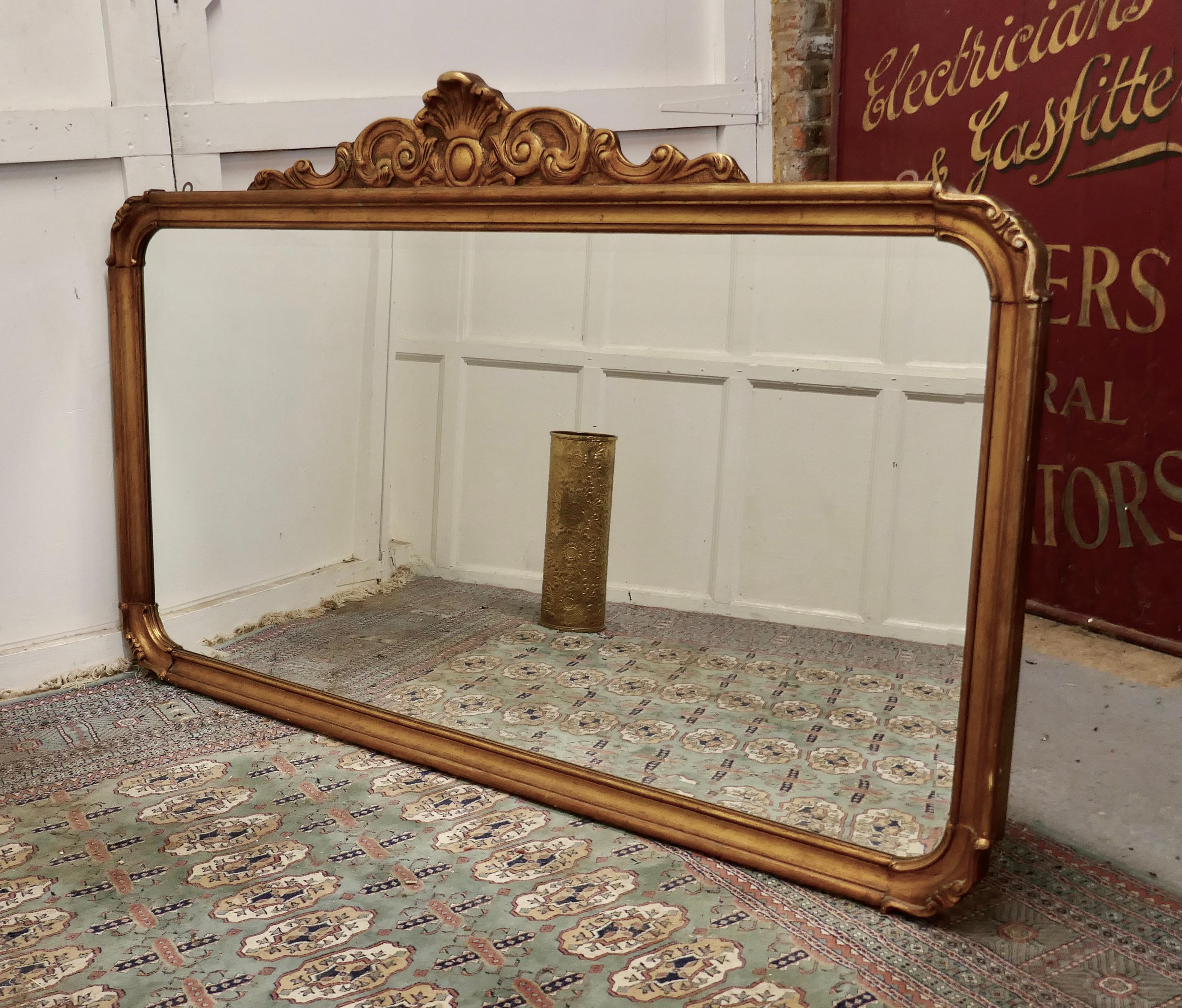 A superb large French gilt overmantel mirror

This is a Striking piece it has a rectangular shape with curved corners there is a carved decoration at the top with entwined leaves and shell 
The mirror is a 20th Century piece in a lovely aged rich