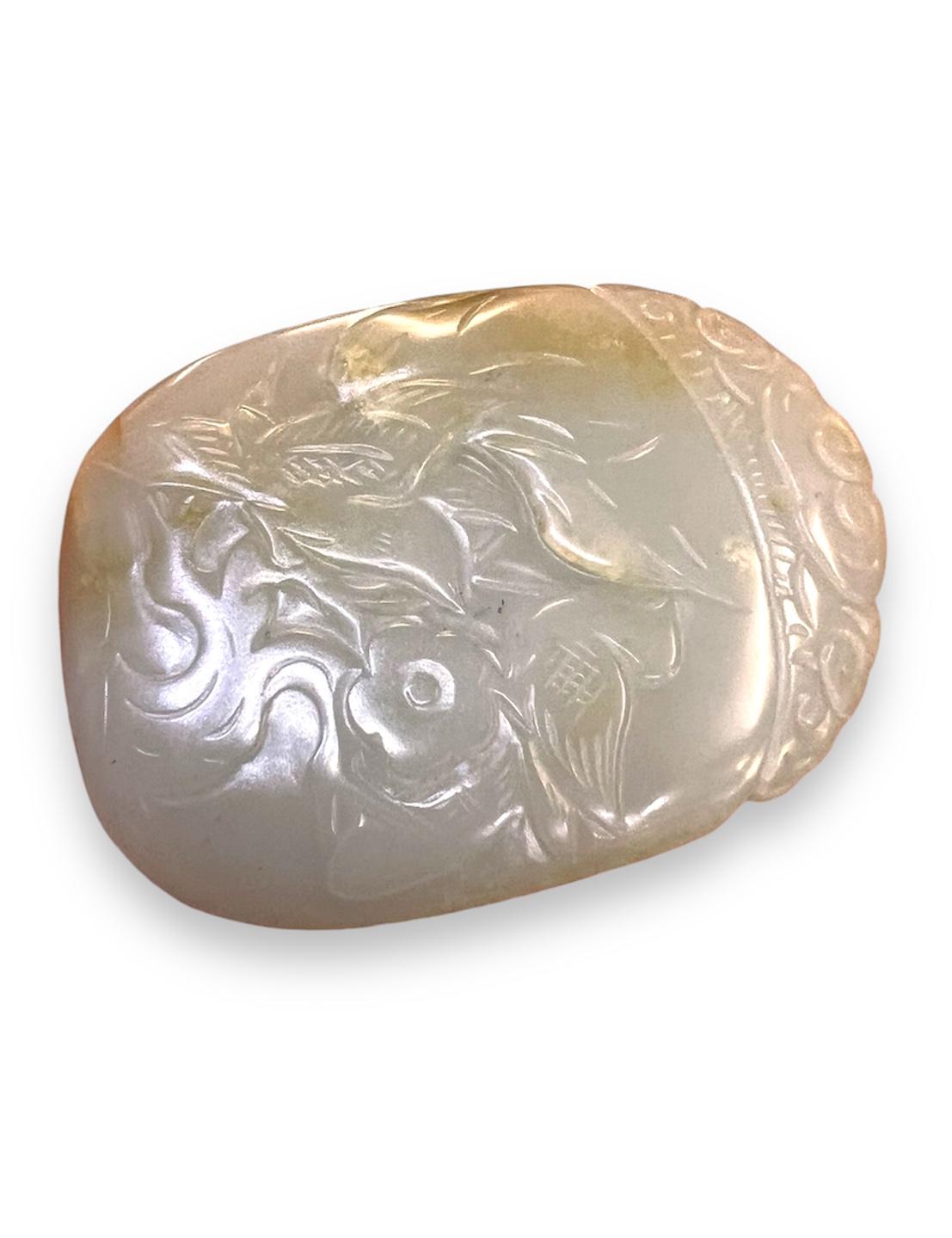 
De forme ovale, finement sculptée en relief d'un oiseau perché sur un arbre, de fleurs et de feuillages, le revers avec un caractère chinois, bien poli, la néphrite de jade translucide de haute qualité est d'un ton blanc avec une inclusion rousse