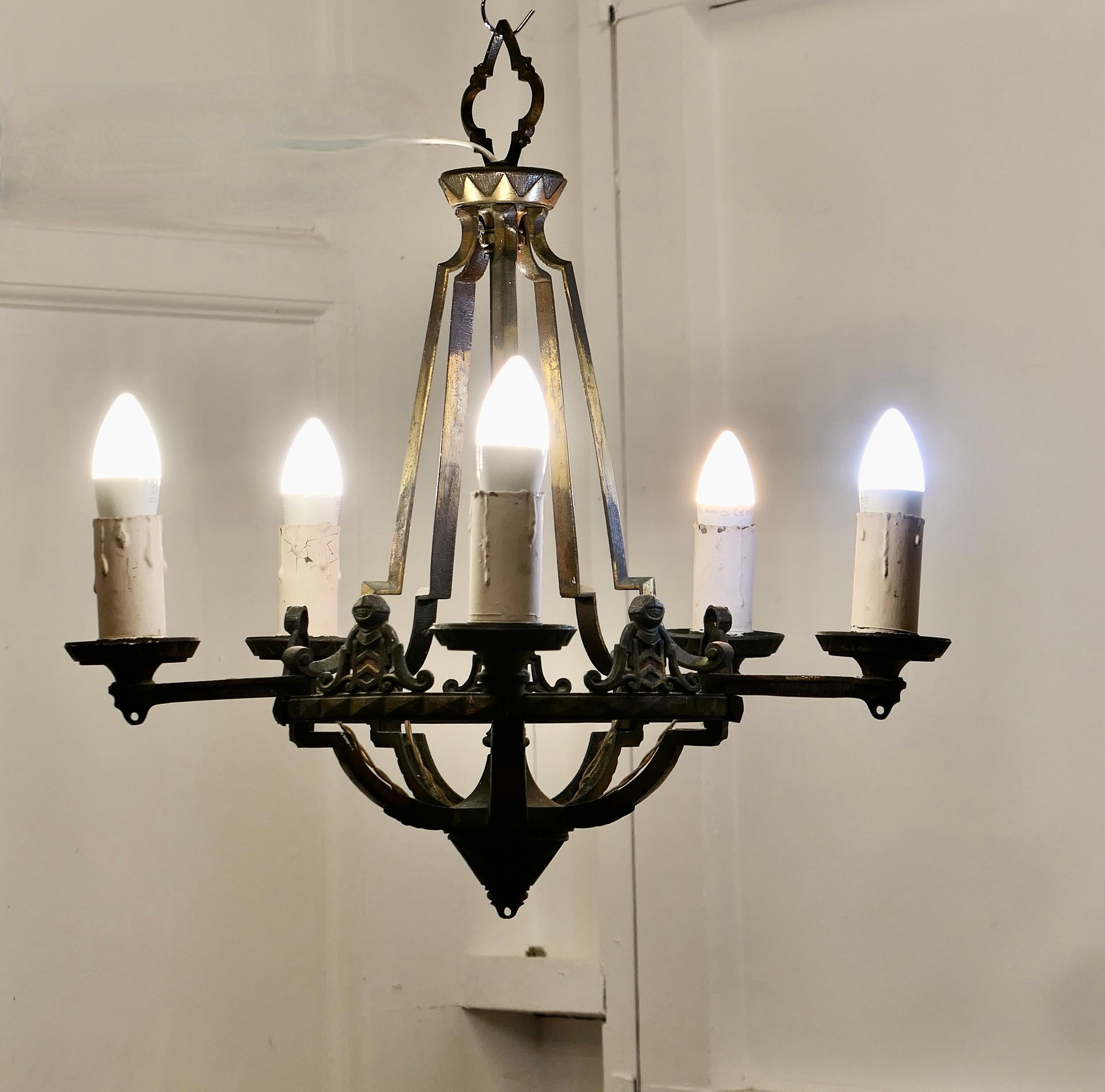 A Superb Medieval Look Iron Ceiling Light

A very handsome piece, the chandelier is Heavy and very Gothic in design, it is made in iron and cold painted much of this is worn away
The lamp has 5 branches and knight’s shields set between each if