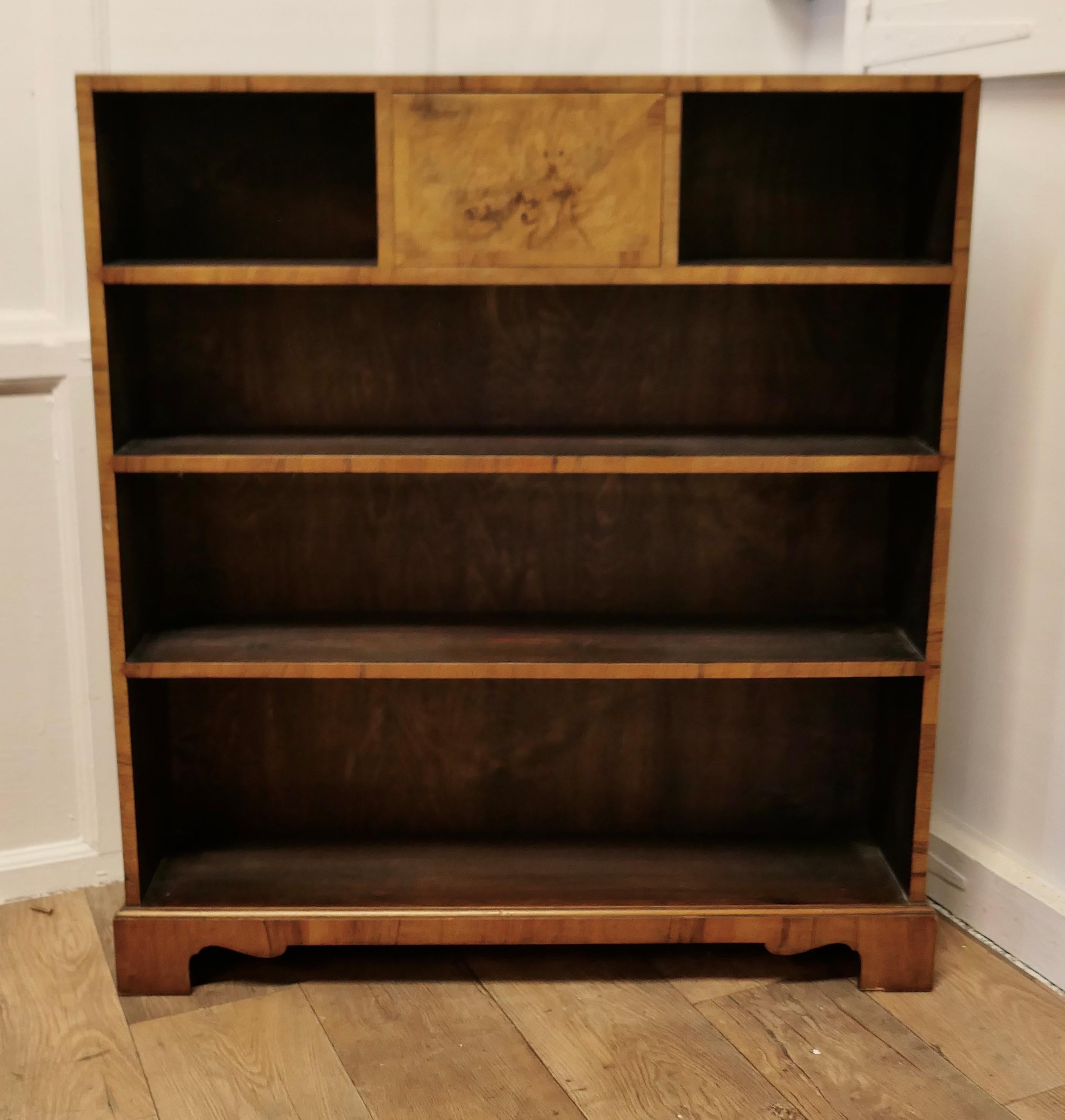 A Superb Odeon Style Walnut Open Bookcase

This is a good quality Art Deco Bur Walnut open book shelf, not completely open as there is a very concealed compartment in the centre of the top shelf and the bookcase stands on a bracket footed plinth
The