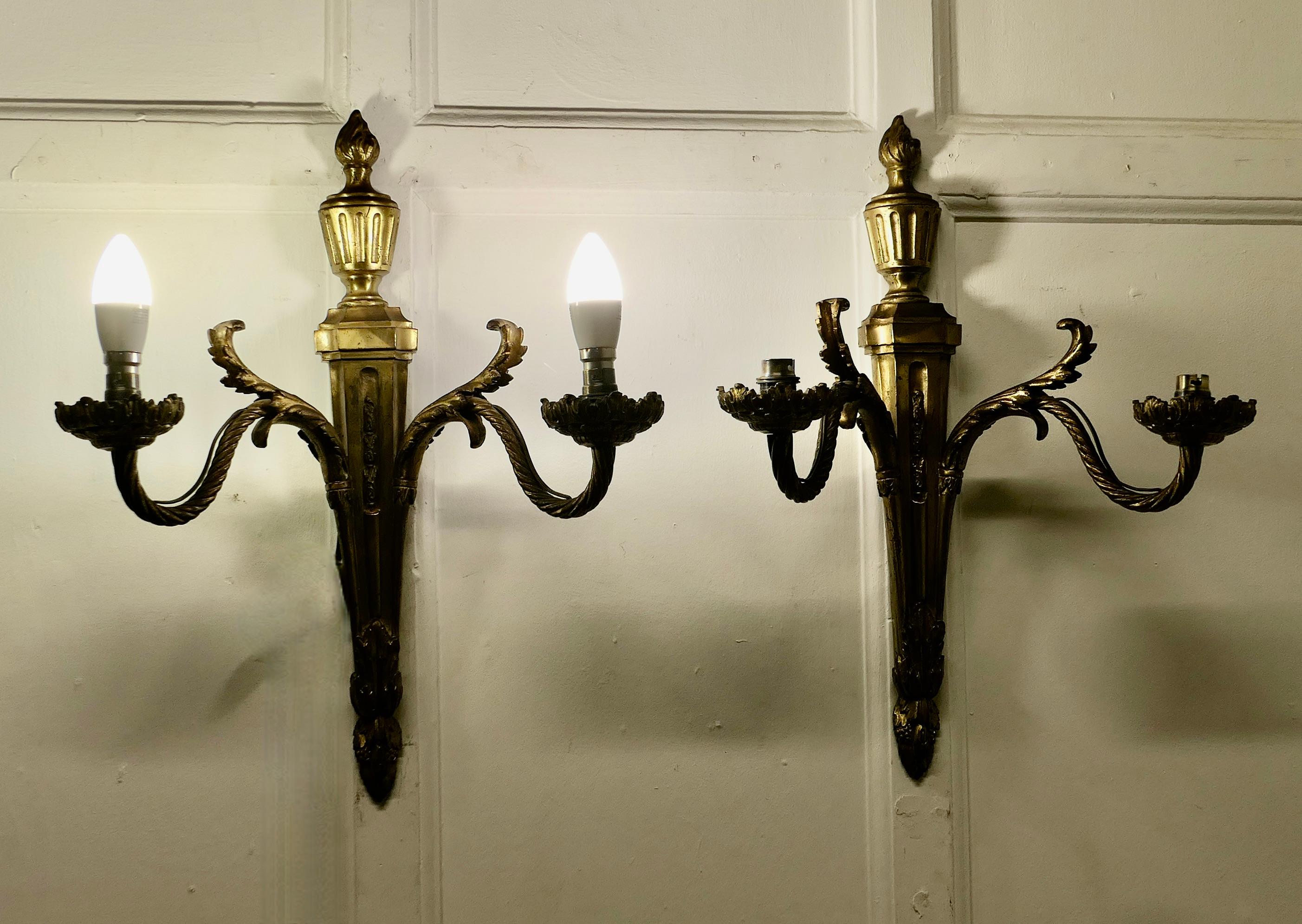 A Superb pair of French Neo Classical Large Brass Wall Lights

A very handsome pair of large very Heavy Brass wall lights, the lights are in the classical style with acanthus leaf and torch decoration each one has 2 fittings each with a sconce
