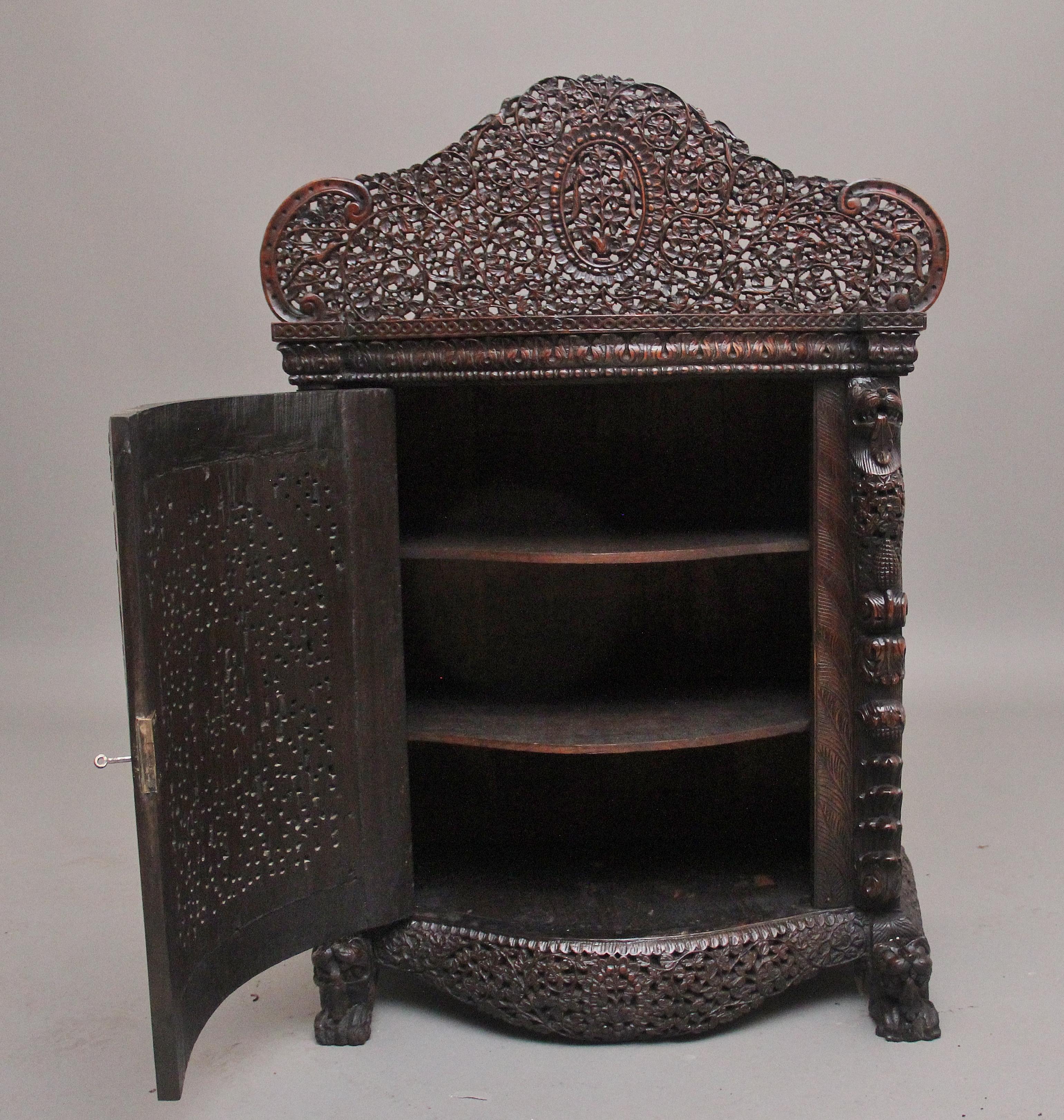 Armadio in legno duro intagliato anglo-indiano di qualità superba della metà del XIX secolo, con un bel piano sagomato a figure con una base altamente decorativa traforata e intagliata composta da vari fogliami con un pannello ovale al centro con