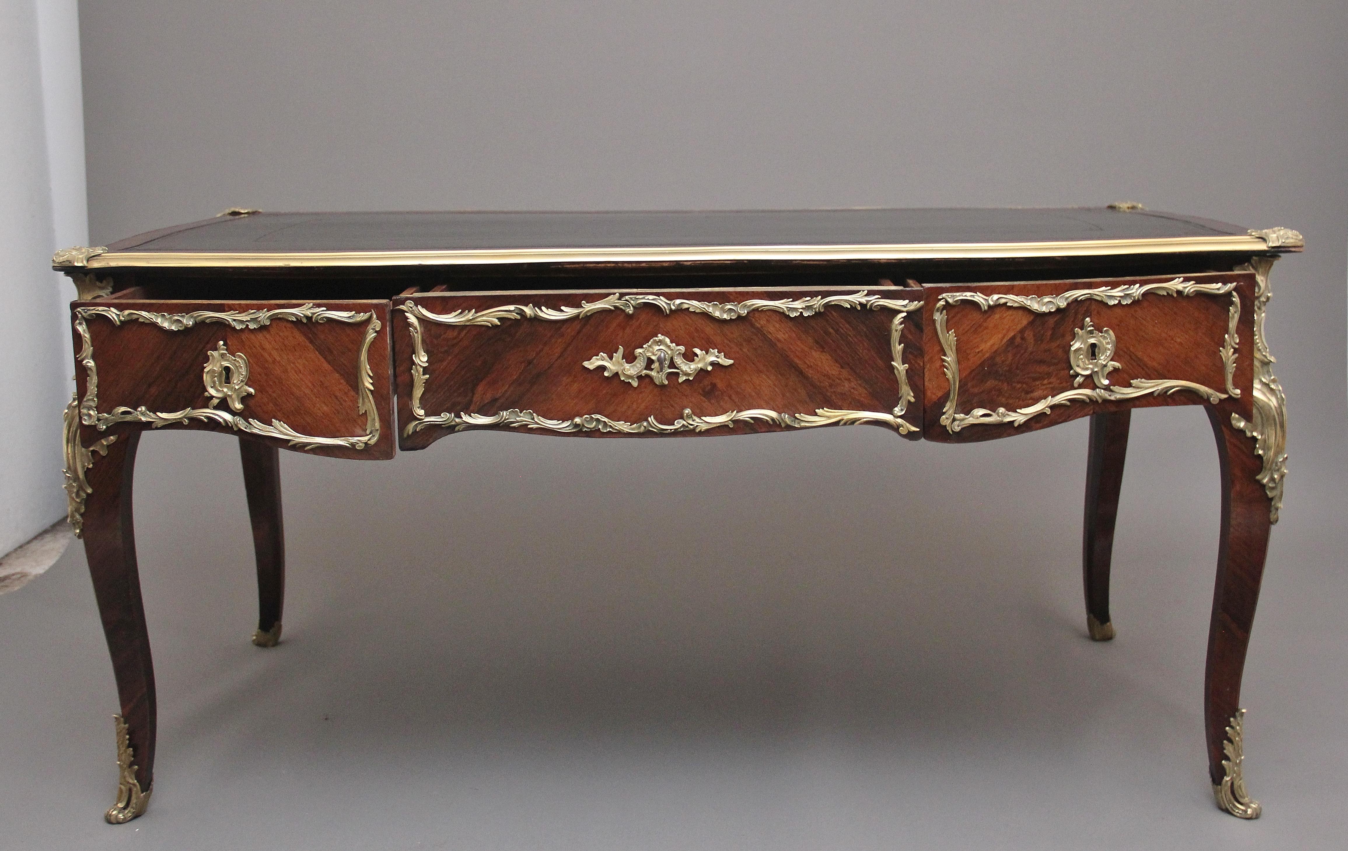 A superb quality 19th century French Kingwood and ormolu mounted bureau-plat desk, having a shaped top with an ormolu moulded edge, decorative shell engraved corner mounts, kingwood cross banding around the edge and a green leather writing surface
