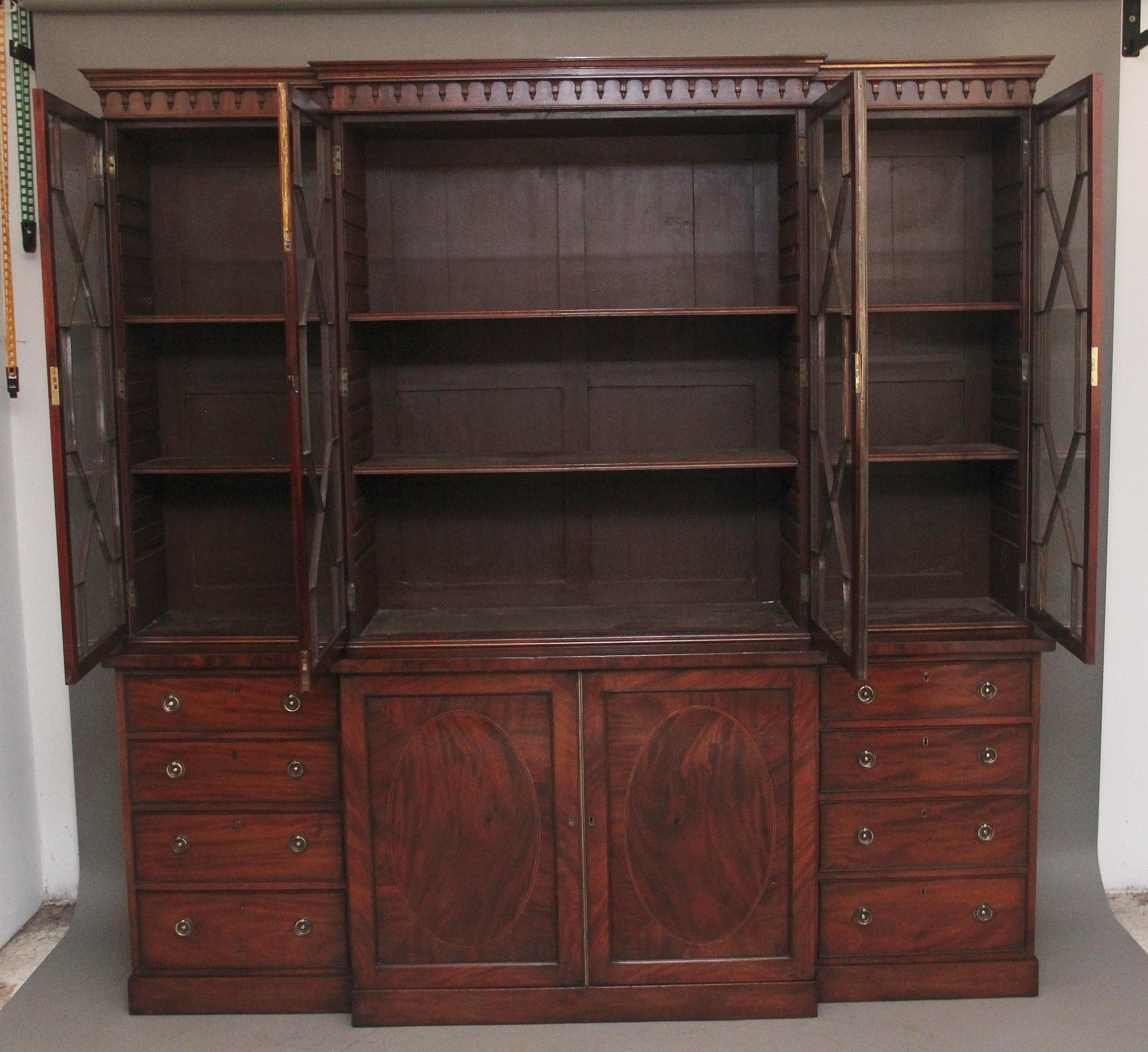 A superb quality early 19th Century mahogany breakfront bookcase, the stepped moulded cornice with carved decoration below above four large astrigal glazed doors opening to reveal two adjustable shelves inside each section, the bottom section having