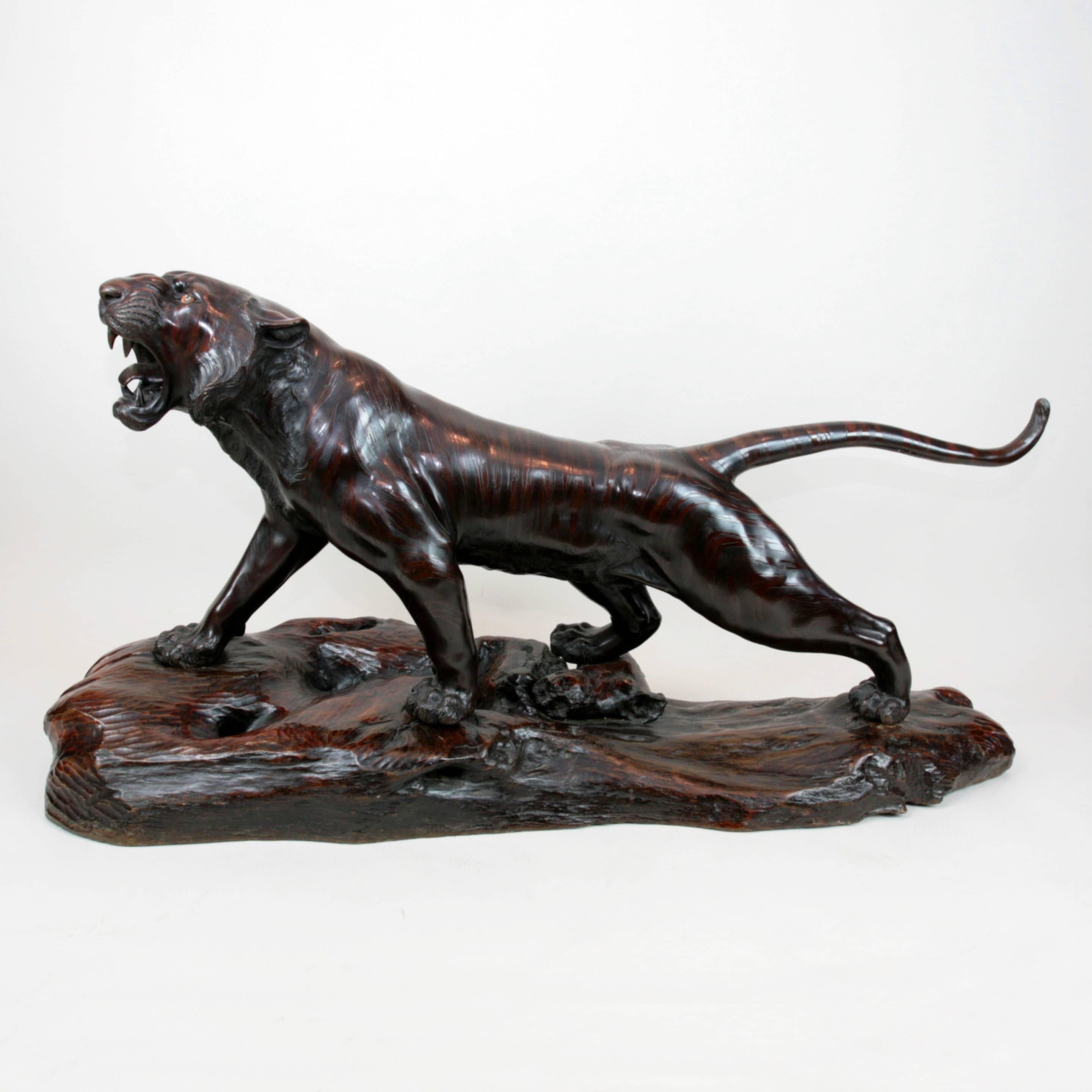 Una superba tigre in bronzo a grandezza naturale, con il corpo in bronzo patinato per imitare le strisce distintive della pelle della tigre e gli occhi in vetro arancione incastonati. Firmato in un sigillo tsunematsu. Su una base in legno duro