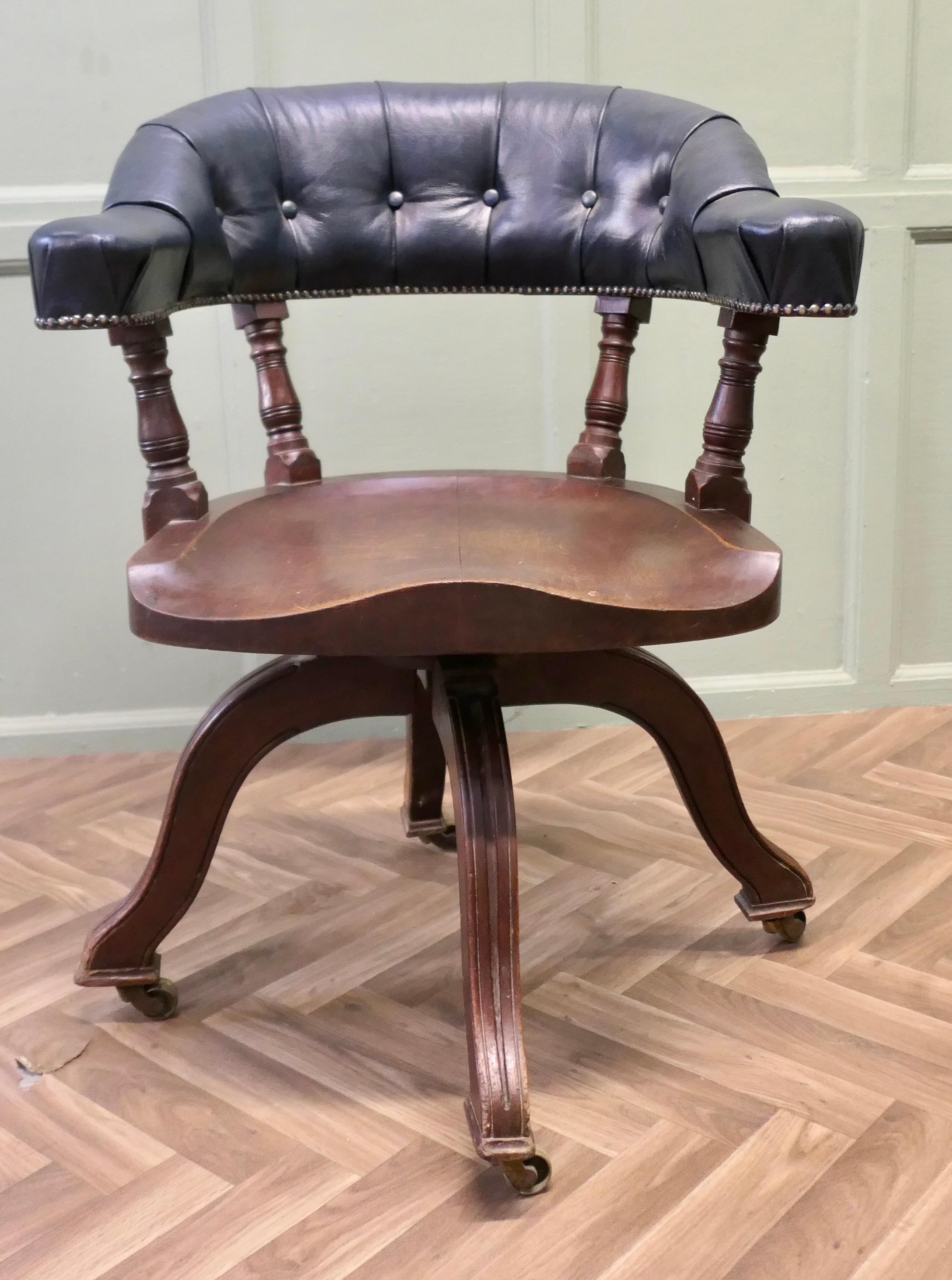 Una silla de escritorio giratoria del siglo XIX magníficamente cómoda 

La Silla tiene una barra superior profundamente curvada que forma los apoyabrazos y el respaldo, está tapizada en cuero azul oscuro profundamente abotonado que proporciona gran