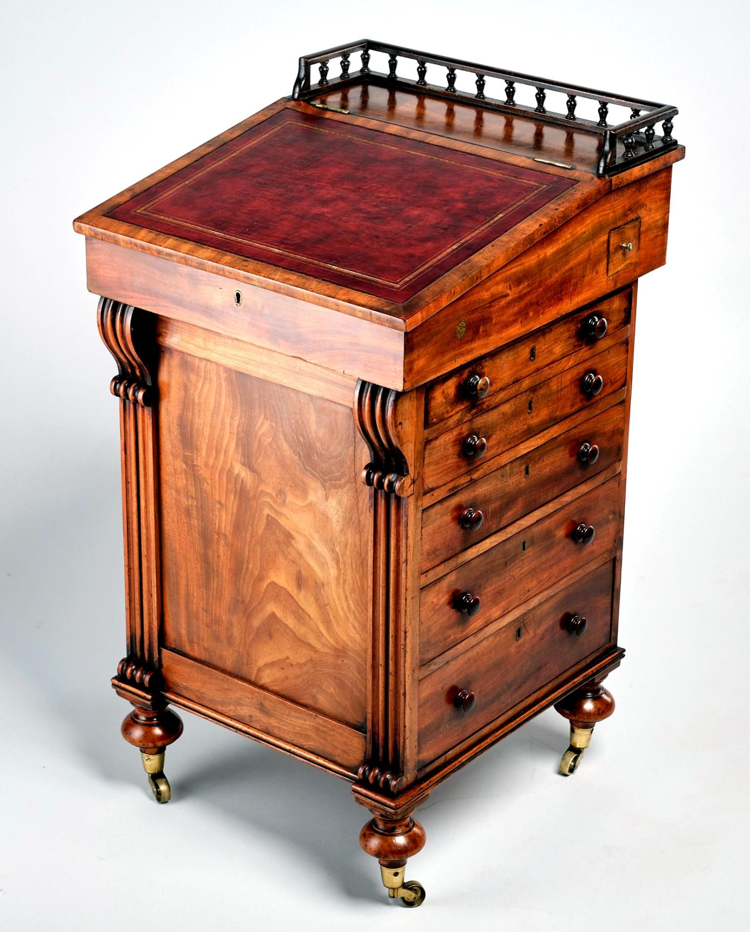 The richly figured mahogany case showing a finely turned baluster gallery over a hinged leather topped writing compartment, opening to an interior fitted with small drawers with satinwood fronts & turned pulls. 
The writing compartment having the