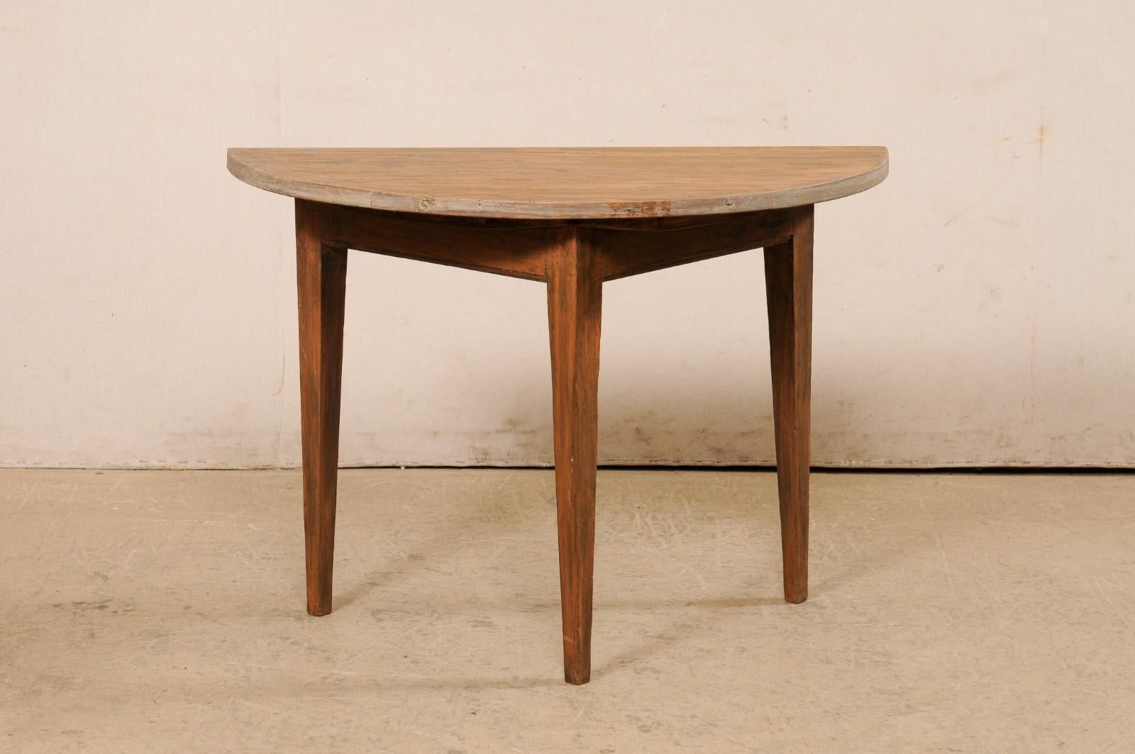 A Swedish single wooden demi-lune table from the 19th century. This antique table from Sweden features a semi-circular, or half moon top, over a triangular shaped apron. The skirt is clean and plain, and the piece is raised upon three squared legs