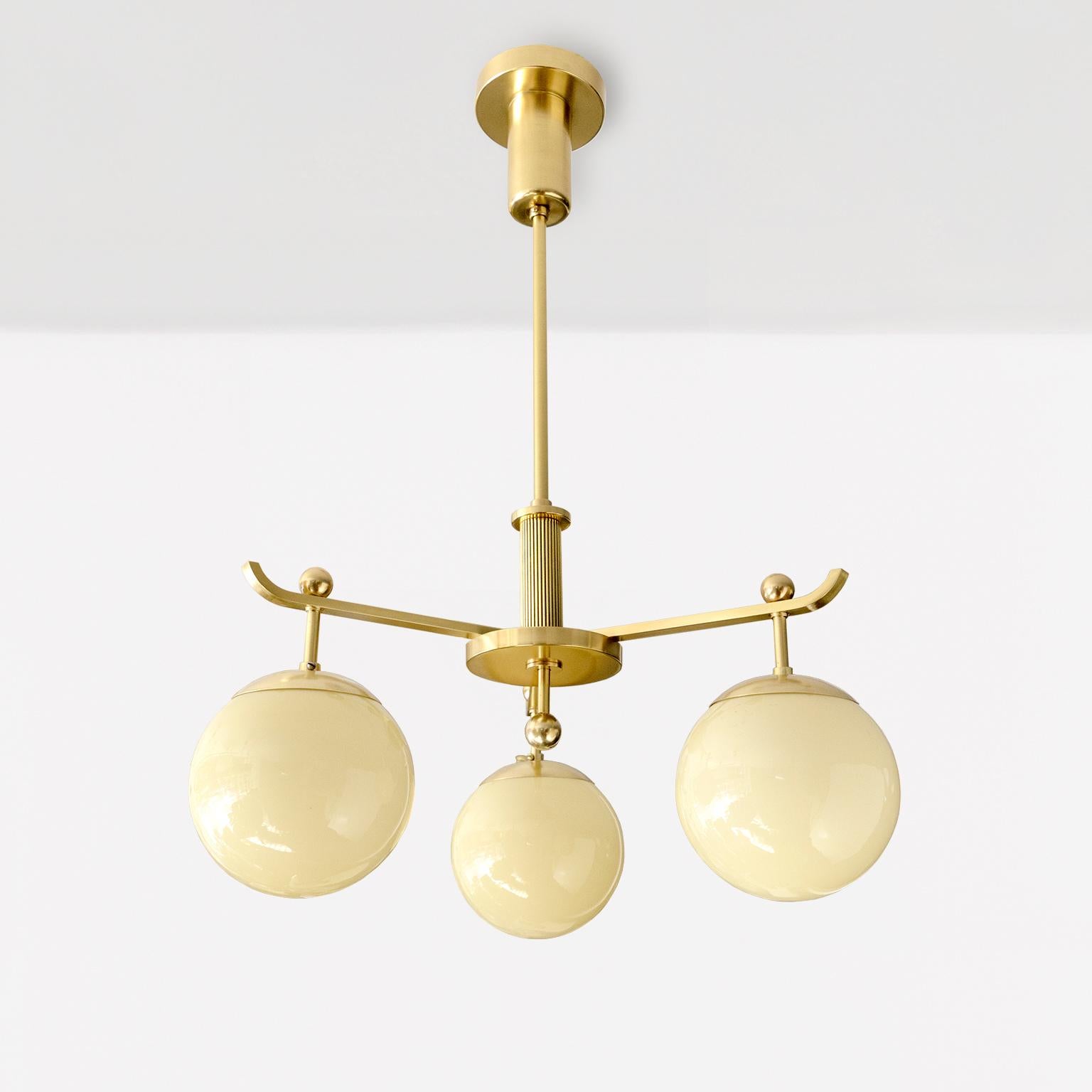 A Swedish Art Deco polished 3-arm brass chandelier with glass globes. The overall design is a play on balance between the arms, the stem, final, canopy and globes. An elegant modernist lamp fixture from circa 1930.

Newly restored, polished and