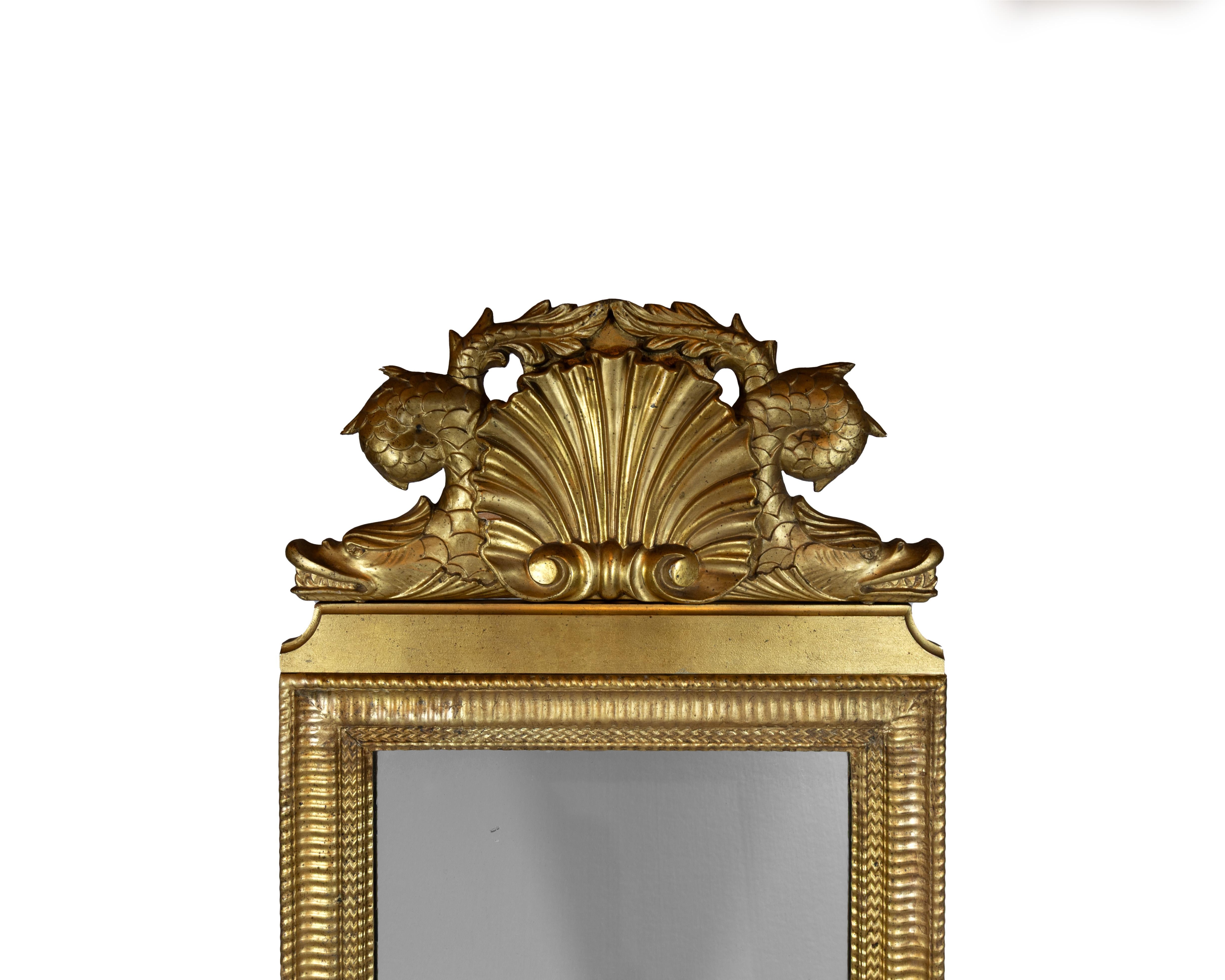 Espejo sueco de estilo gruta con marco de madera tallada y gesso dorado, rematado con una concha de vieira sobredimensionada y flanqueada por delfines, hacia 1880. Se han restaurado los detalles de gesso y el acabado dorado, mientras que la placa de