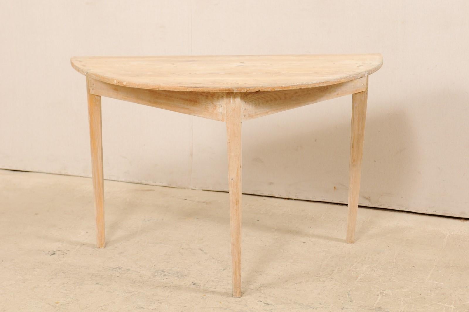 A 19th century single Swedish wood demilune table. This antique table from Sweden features a semi-circular, or half moon top, over a triangular shaped apron. The skirt is clean and plain, and the piece is raised upon three squared and gently tapered