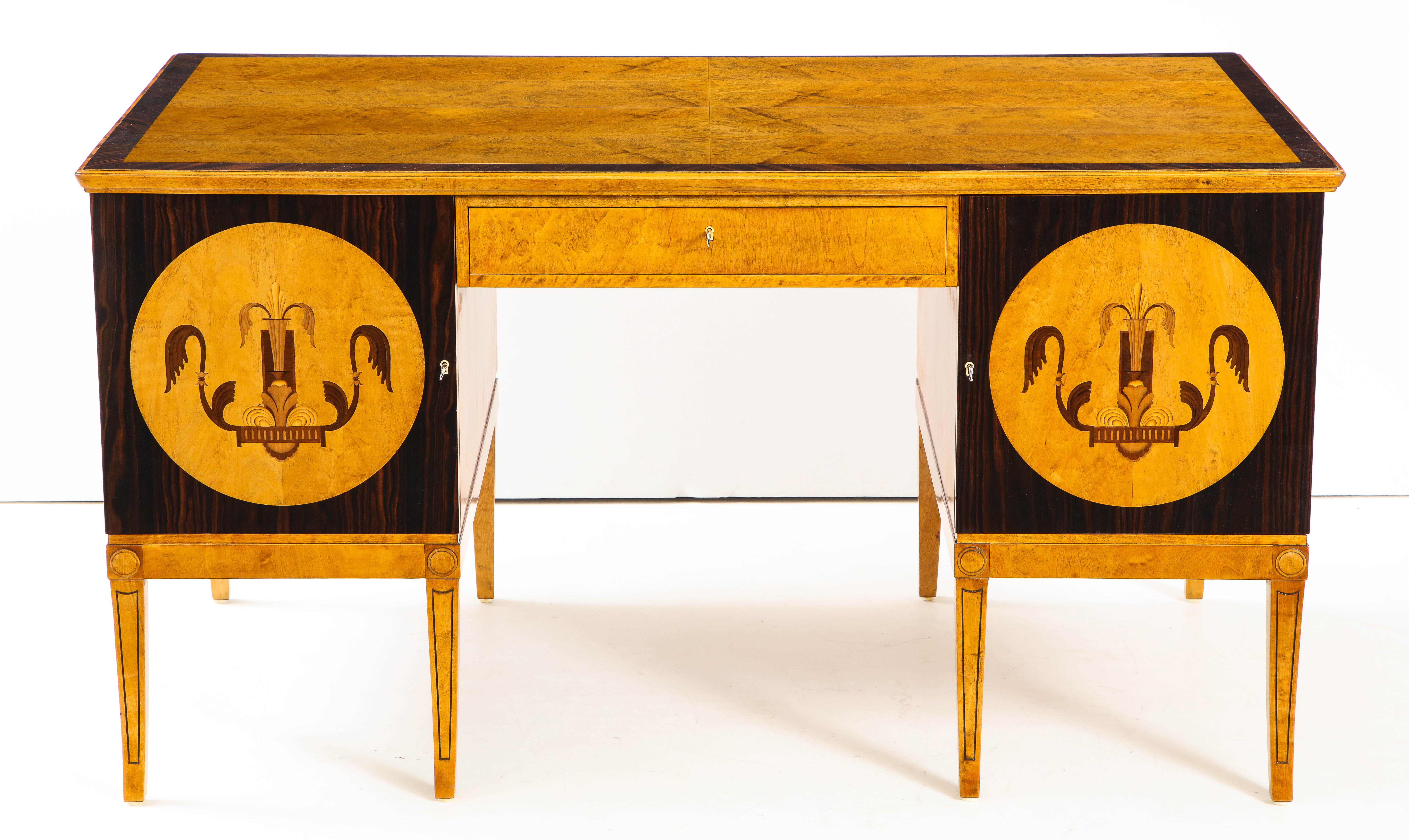 A Swedish Grace birch wood and rosewood pedestal desk, circa 1930-1940, the rectangular birch top with rosewood crossbanding, slightly rounded corners above a single frieze drawer. Both pedestals with inlaid cupboard doors opening to interior