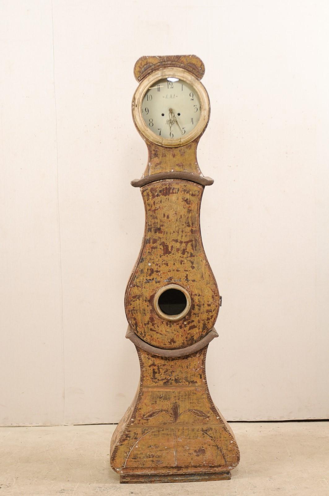 A 19th century painted wood Swedish grandfather clock. This antique floor clock from central Sweden is from the 1820s and features a raised crest with flat-top, it's original round metal face & movements, a raindrop shaped belly, a curvy triangular