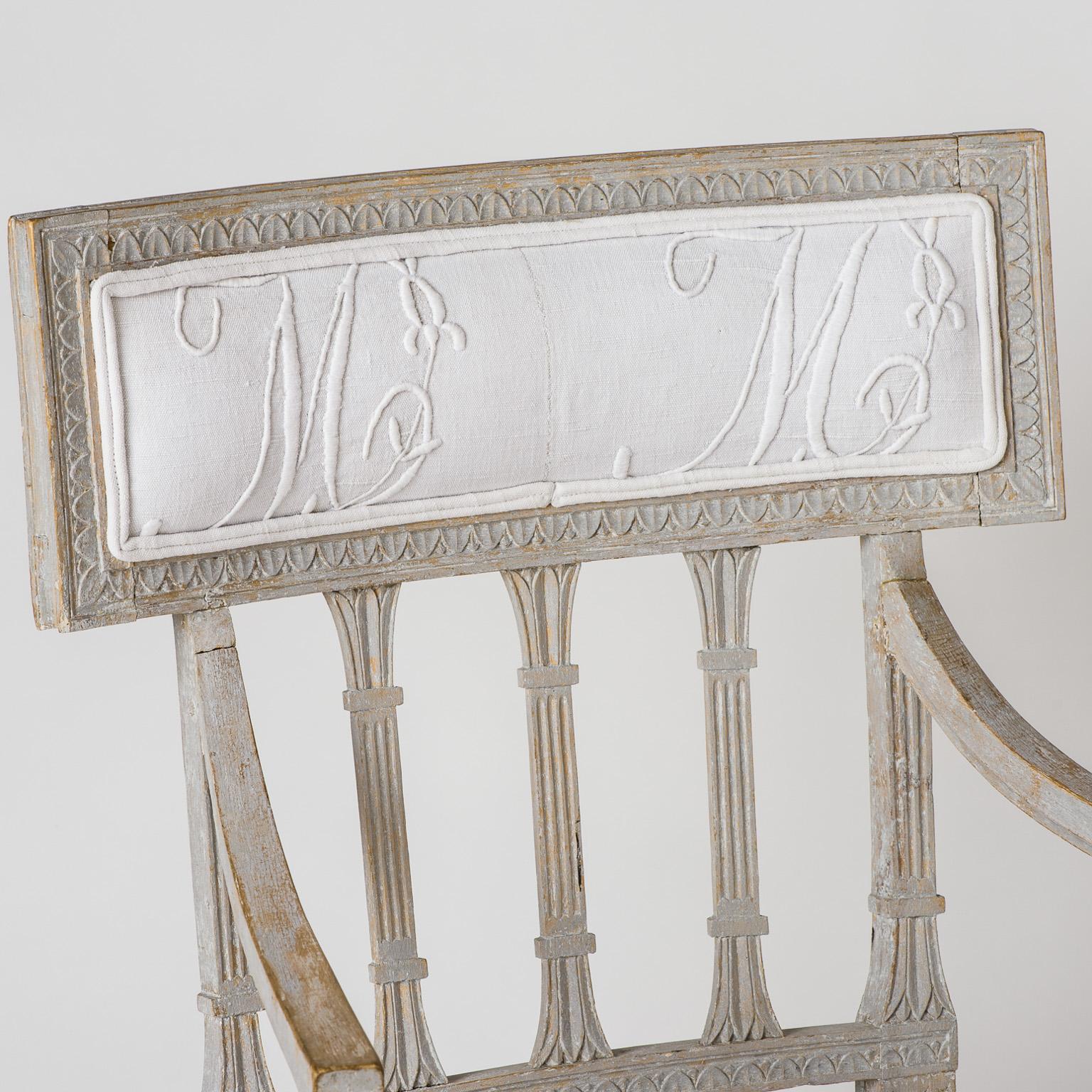 This elegant chair is a beautiful example of the best of Gustavian style with its sleek reeded back splats in the lotus pattern and detailed carvings on the legs and apron. The pale grey paint is original and has a beautiful patina. The chairs have