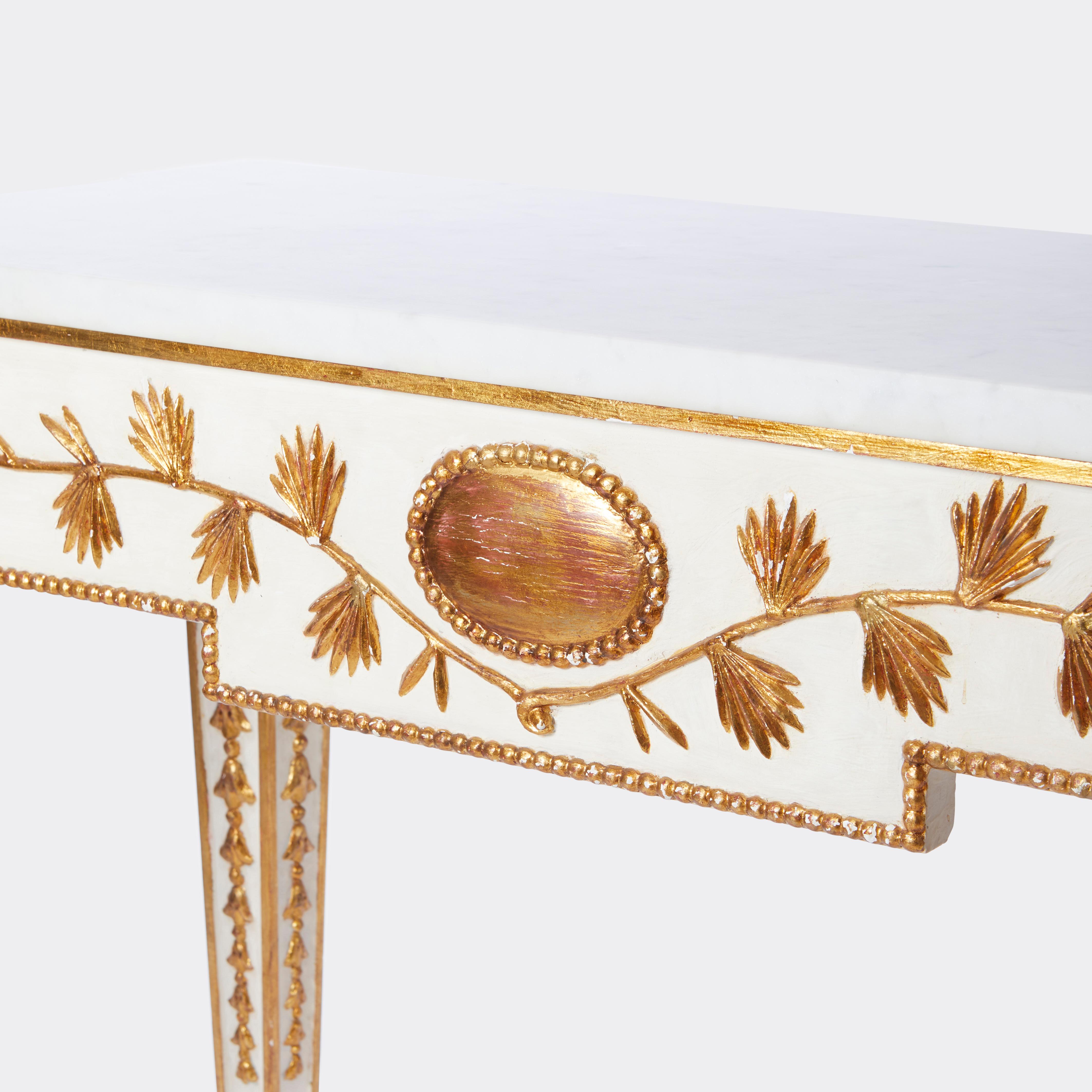 A pair of Swedish Gustavian-style console tables with four square tapered legs carved in gilt bellflower garlands of graduated size. The block extended quarters with hand carved rosettes and an apron with laurel leaf carved decorations bellow the