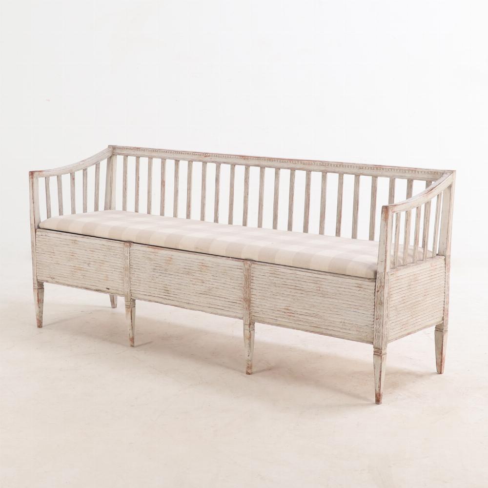 Questa panca meravigliosamente shabby chic ha uno schienale dritto e braccioli leggermente ribaltati, tutti sostenuti da fusi piatti e da una lunga seduta rettangolare, appena imbottita e sollevabile, che si apre per rivelare un pratico vano