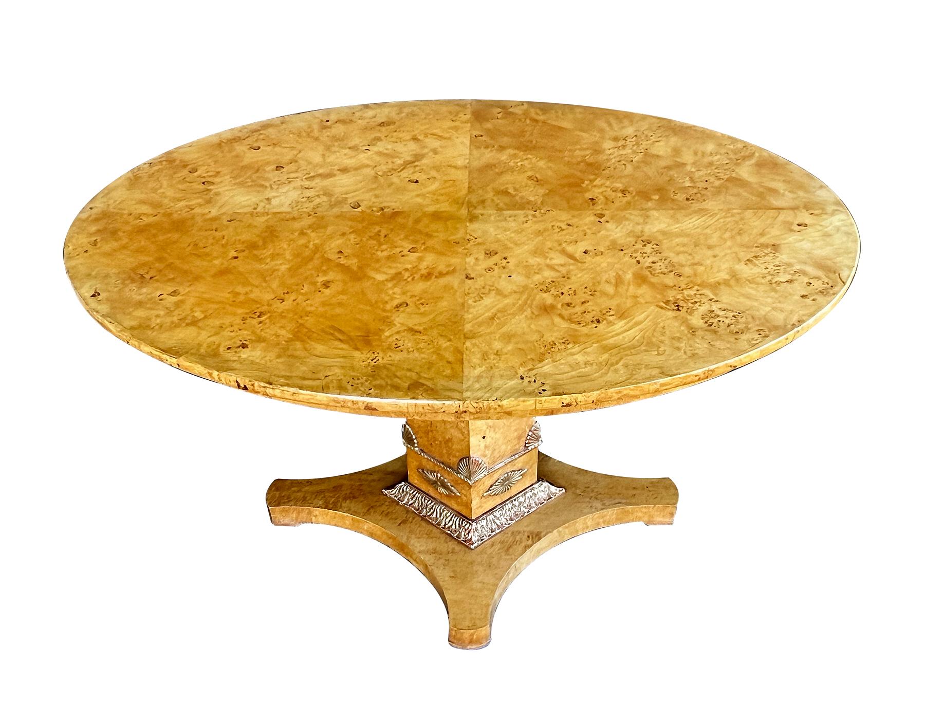the well-figured quarter-veneered oval top above a plain frieze apron raised on a graduated quadrangular pedestal adorned with giltwood anthemion decoration above a giltwood foliate perimeter band; all resting on a concave quadruped base
