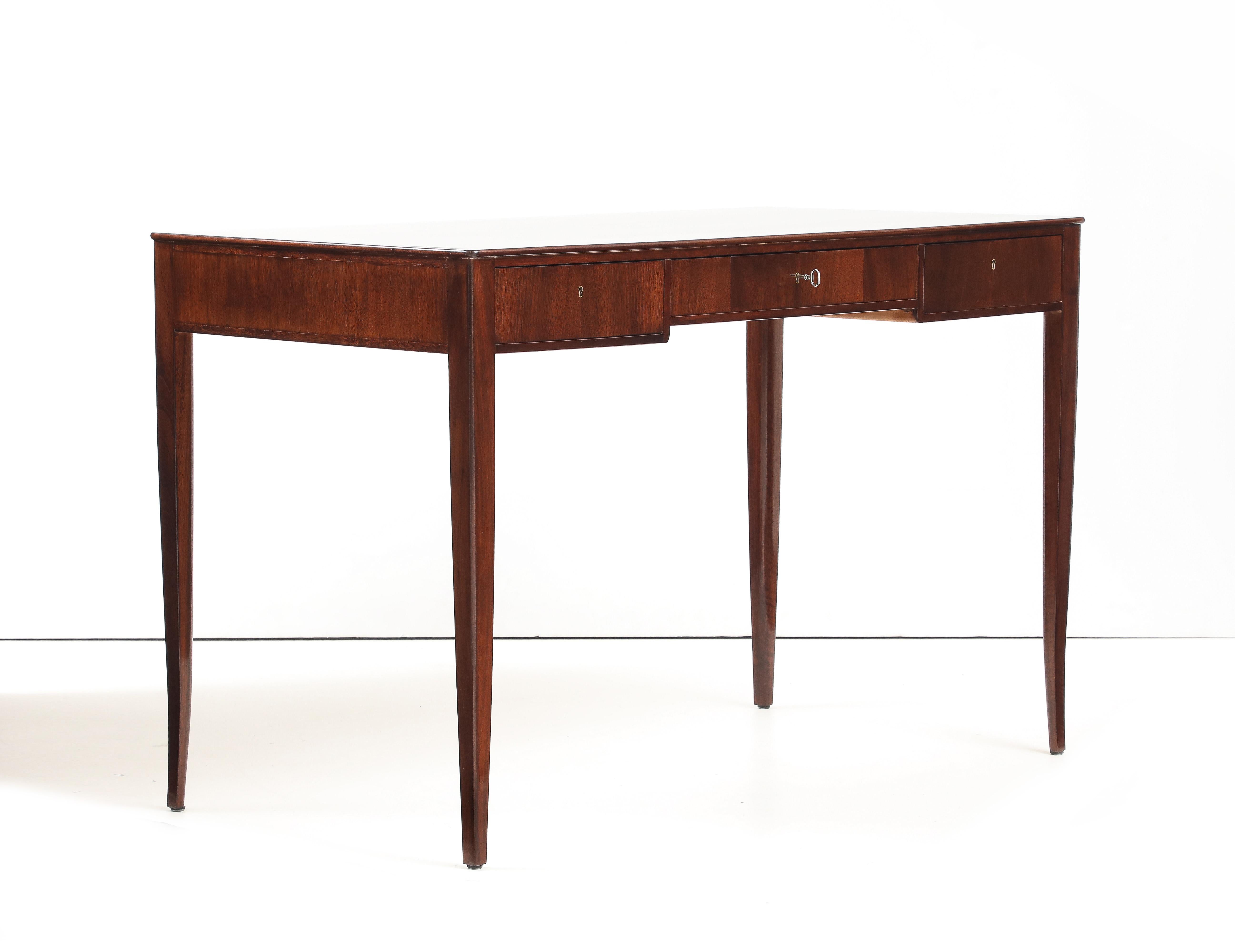 A Swedish mahogany writing desk designed by Carl Malmsten Circa 1966, named Guldheden, produced in collaboration with NK (Nordiska Kompaniet), the rectangular top with rounded corners above three frieze drawers raised on tapering legs.