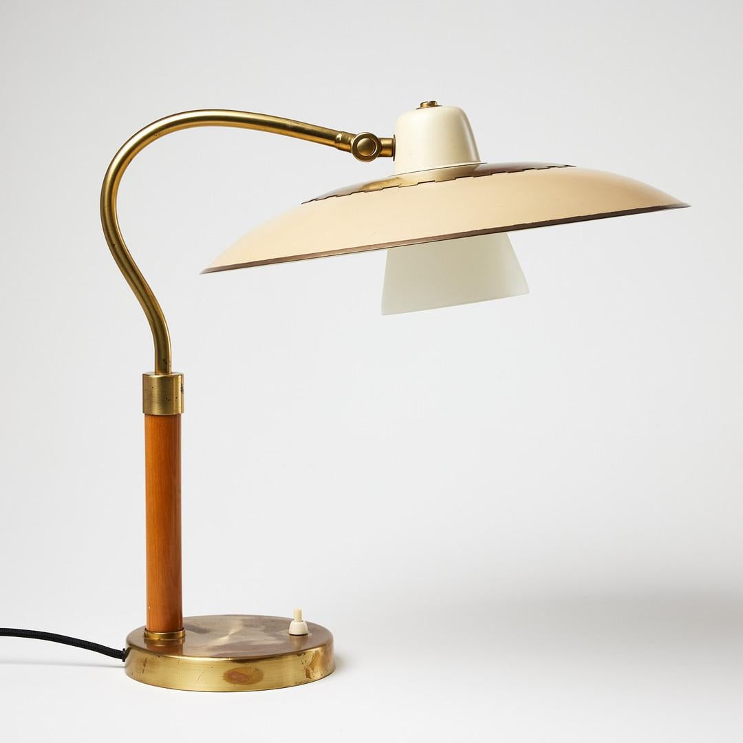 A classic Swedish Modern table lamp from the 1940s, designed by Boréns Borås. Featuring a round brass clad base with integrated switch, the pillar is partially clad in lacquered elm. The elegant brass arm curves into a circular lacquered metal shade