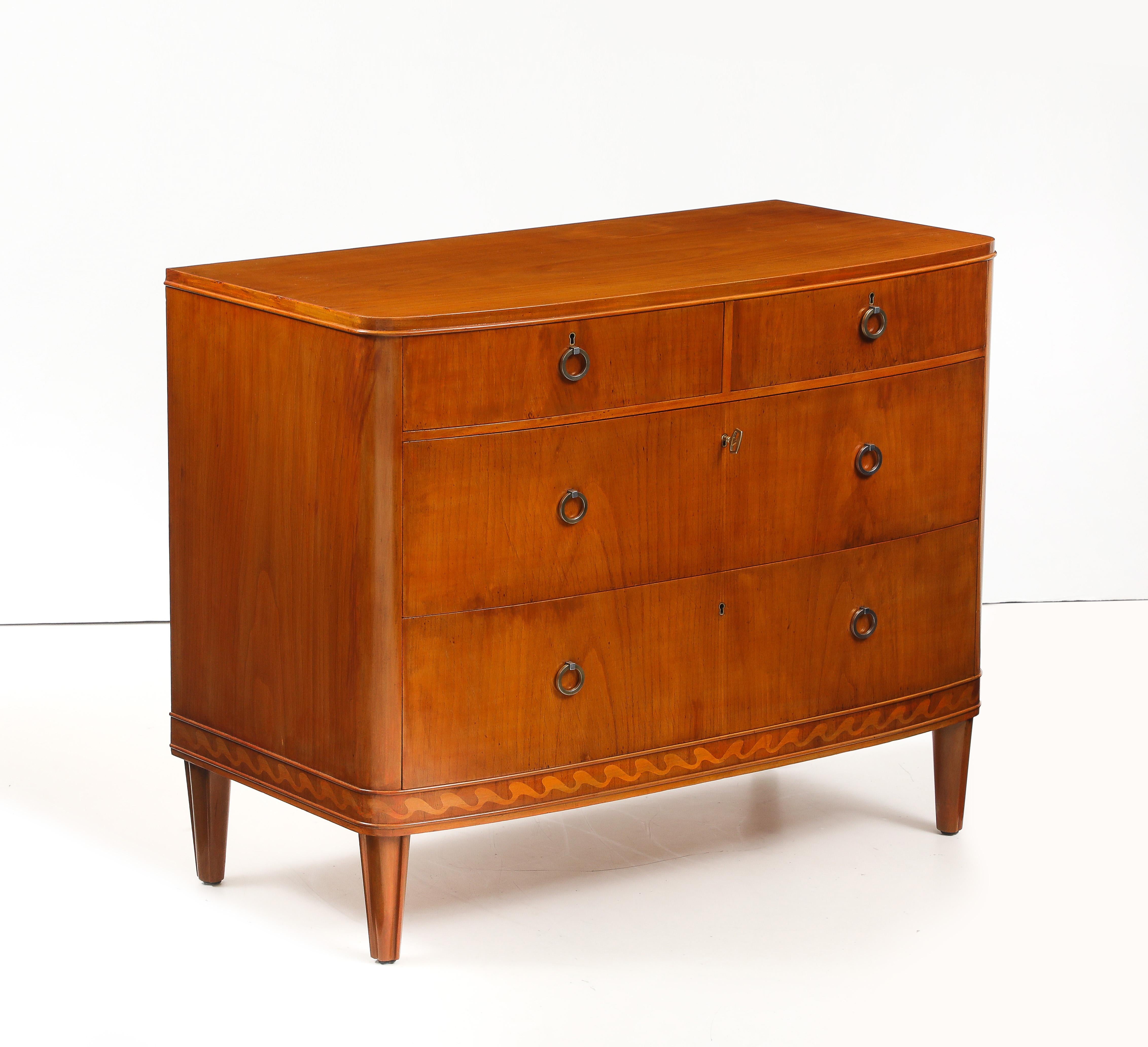 Cassettiera svedese in radice di olmo e intarsiata, CIRCA ANNI '40, di Nordiska Kompaniet (etichette dei produttori nel cassetto superiore), con un fronte curvo sopra due cassetti corti e due cassetti lunghi. Un fregio inferiore con un'onda di