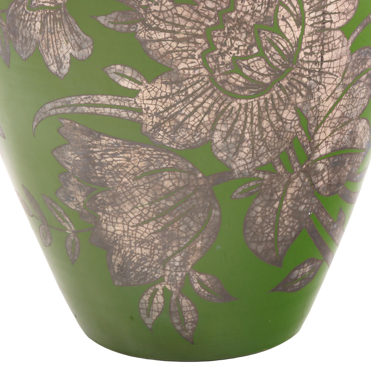 This elegant vase features a classic baluster form, adorned with intricate floral motifs in silver overlay that stand out beautifully against its rich, deep green patinated bronze base. The combination of the verdant hue and shimmering silver