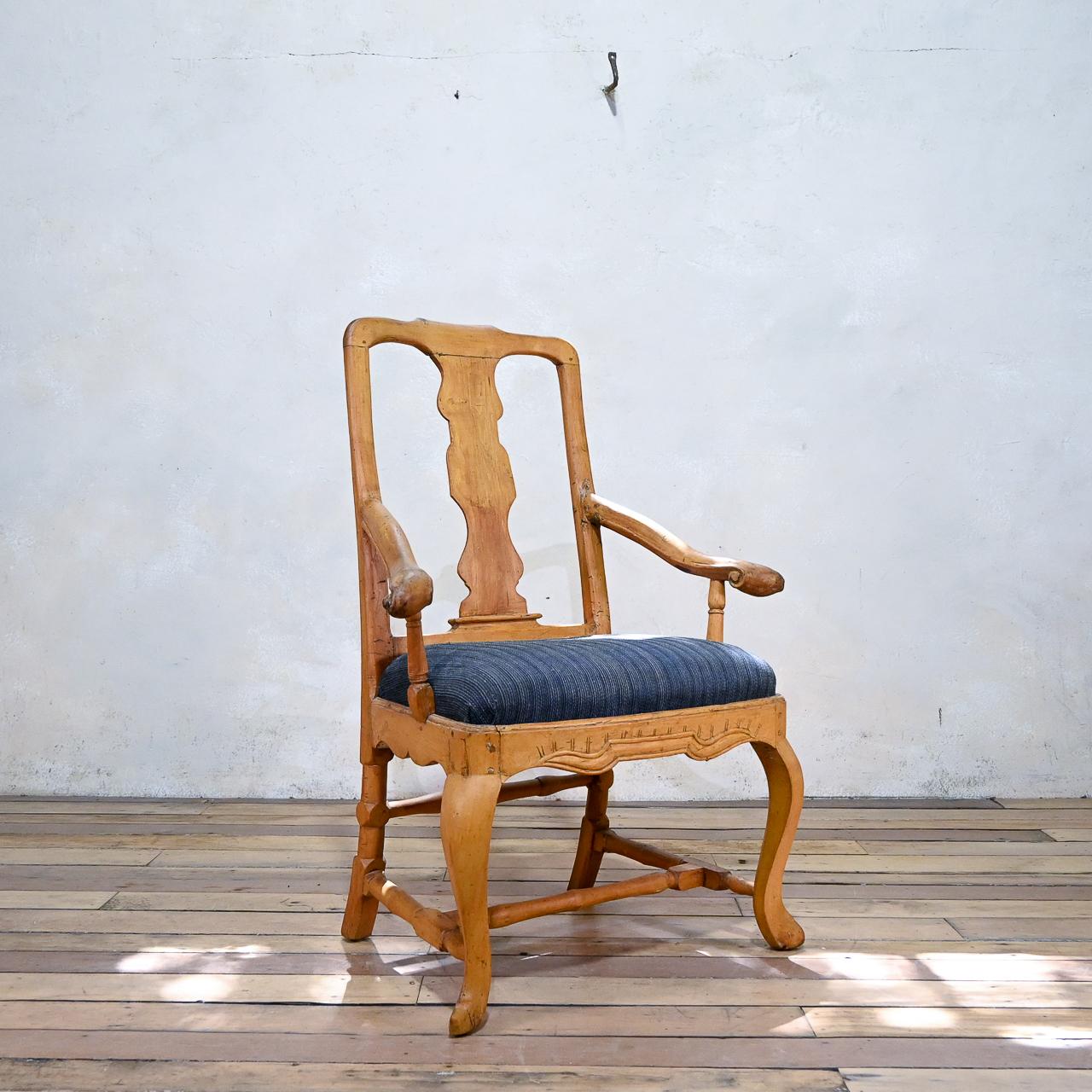 A Swedish rococo 18th century open armchair in original colour displaying its natural wood. Featuring a pierced splat back, raised on, cabriole legs, united by a cross stretcher. A rectangular padded inset seat, flanked by splaying arms with