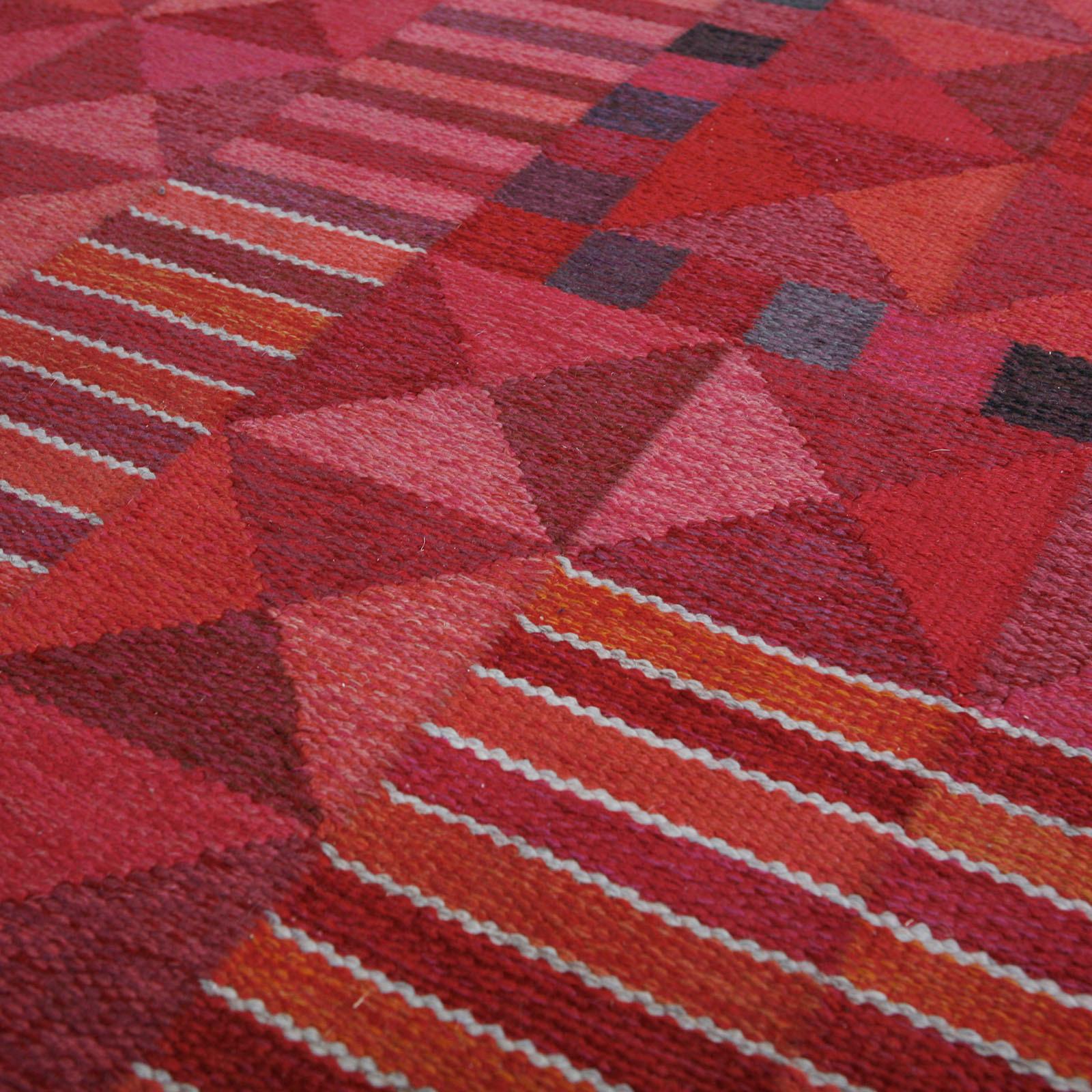 A large rug in vibrant red and orange hues in a geometric pattern. Pure wool in rölakan flat-weave technique.
Designed in 1958 by Swedish textile artist Marianne Richter, produced by Märta Måås-Fjetterström Studio in Sweden.
Measures: Length
