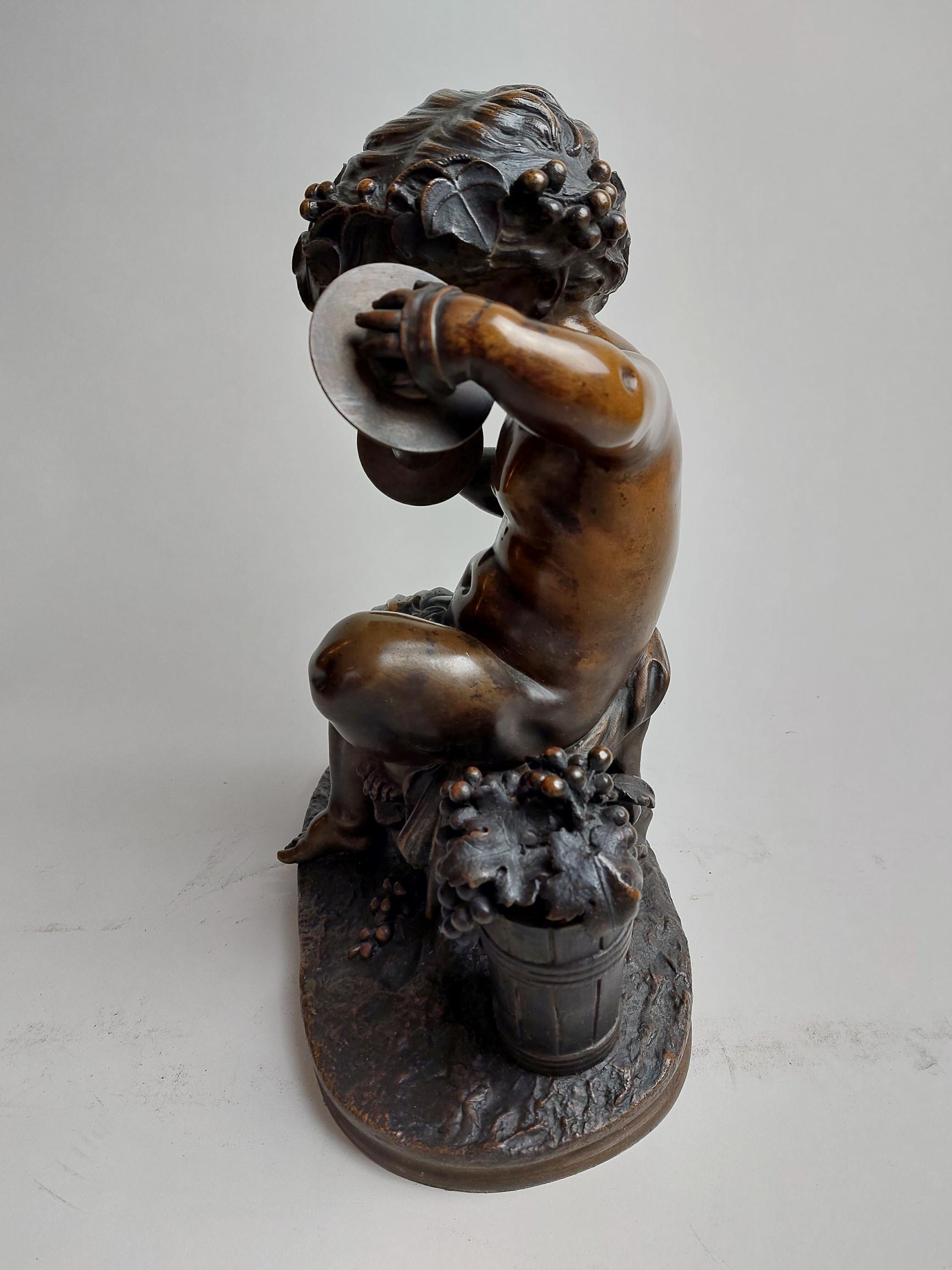 A sweet 19th century bronze of a seated cherub (putto) playing a pair of cymbals, an overflowing basket of grapes stands at his side with more scattered around his feet, suggesting perhaps he is a herald of Baccus the Greek God of wine.