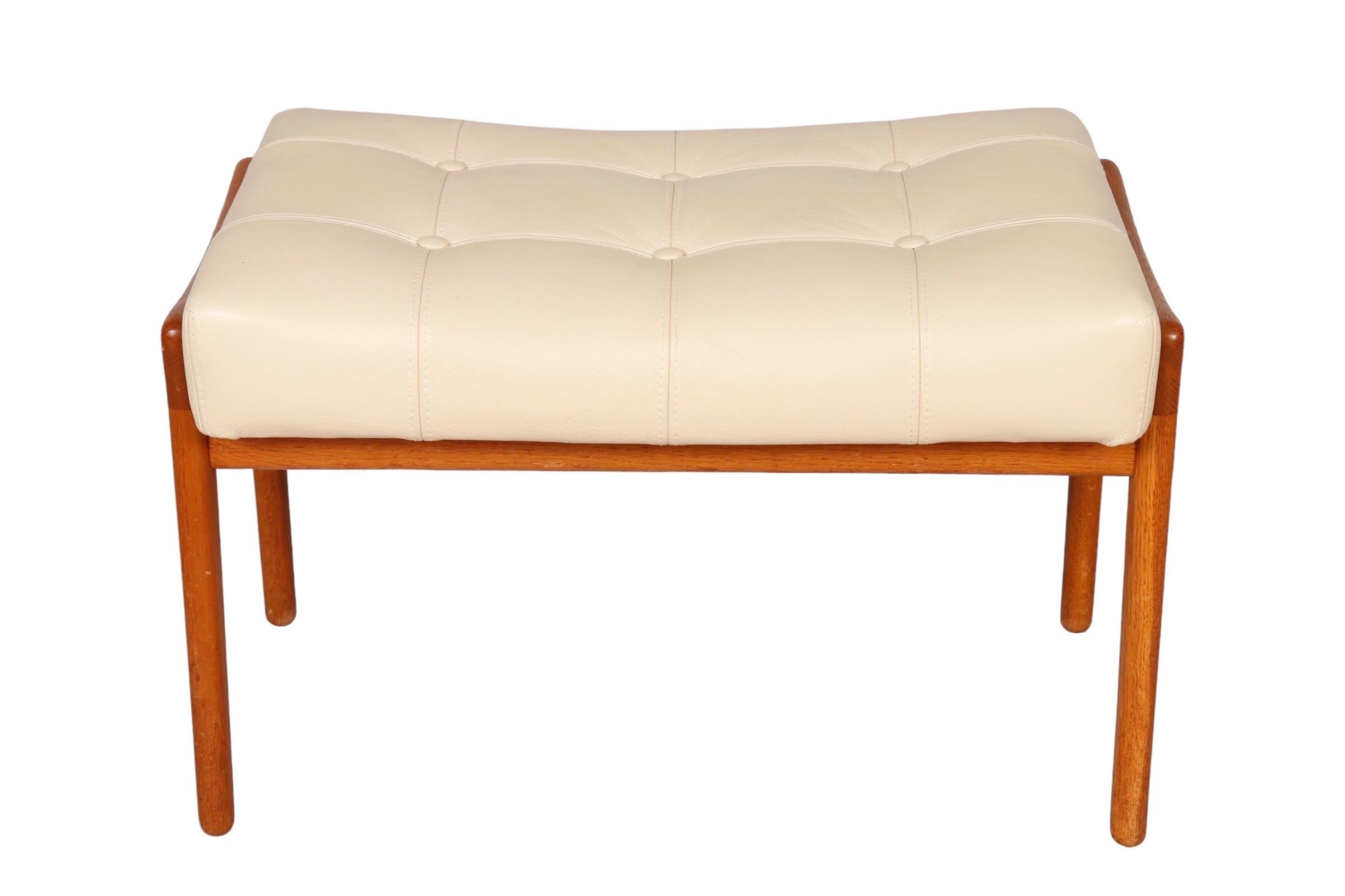 A Swiss Mid-Century Modern ottoman. The frame is made of teak and the seat is upholstered in white faux leather with square button tufting. Marked underneath Arteflo Sa, Arredamenti Interni, Lugano.