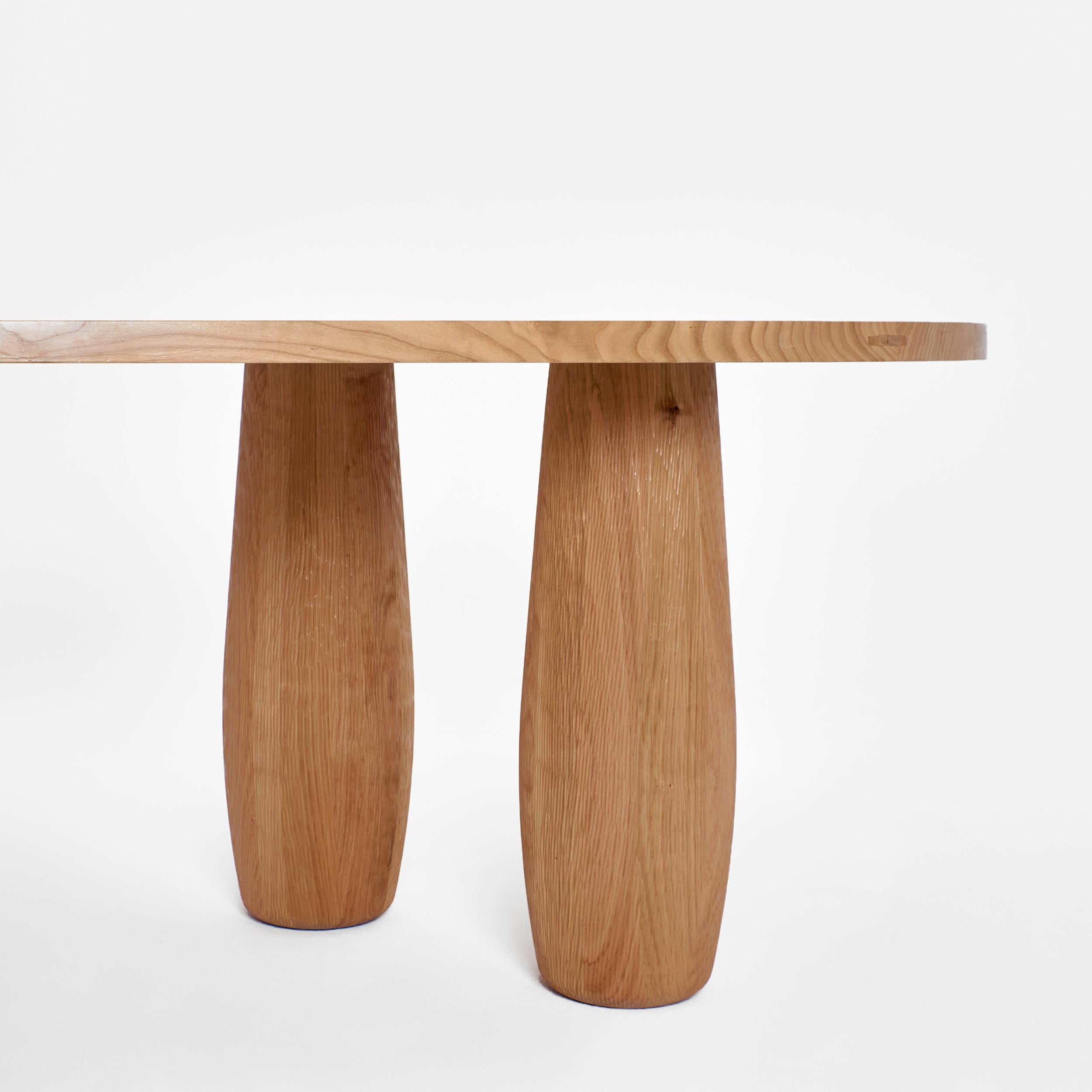 À table - dining table.
An asymmetric table top standing on five oval legs. Each segment carved from an individual piece of cherry wood to showcase the natural flow and texture of the wood with hand carved detailing. The table top features delicate