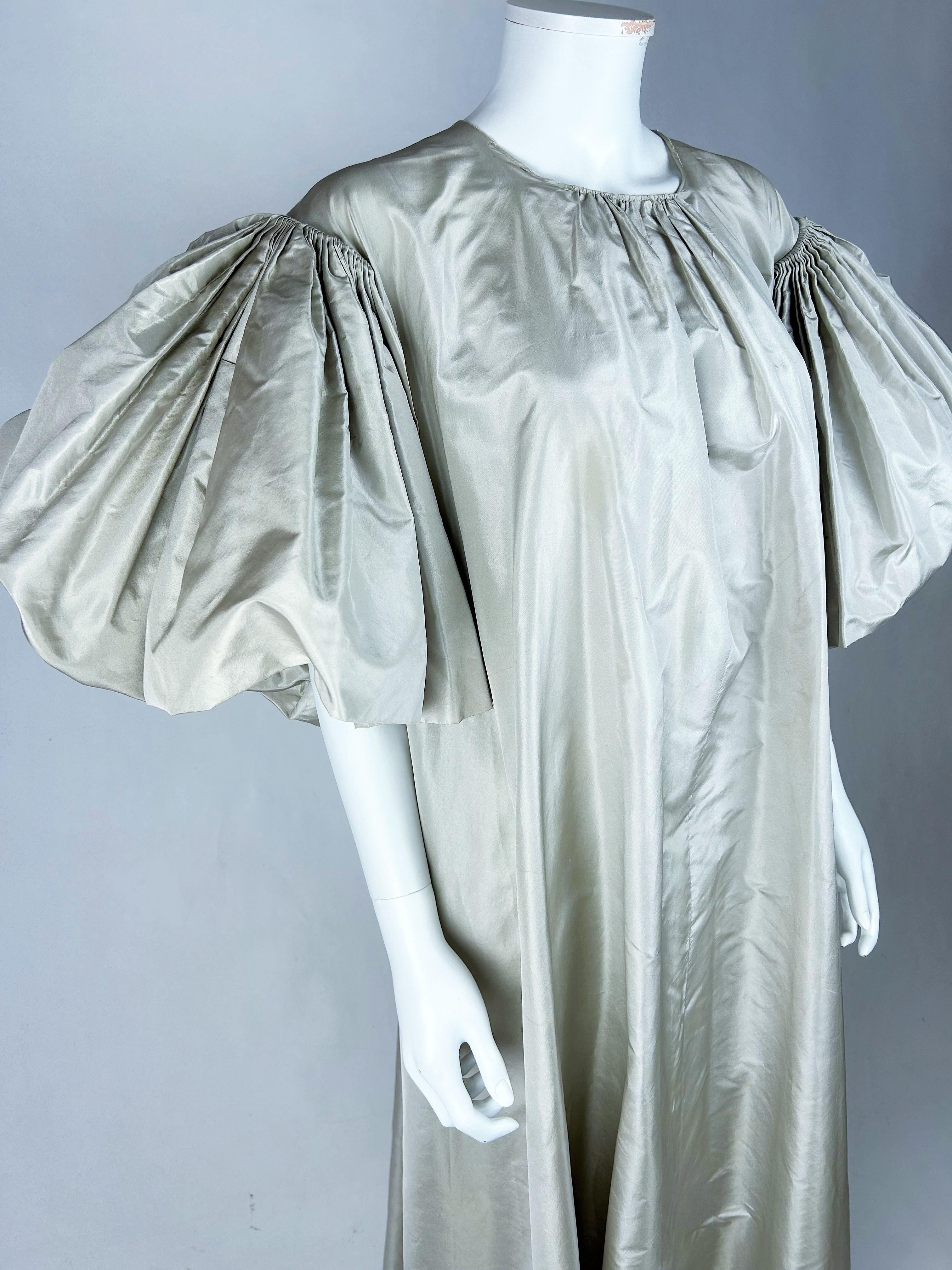 Autumn-Winter 1977 Collection

France

Dramatic long evening gown in pearl grey silk taffeta, in the form of a toga by Madame Grès Haute Couture (attributed to). Chasuble cut with very large bottom, crew neck slightly gathered in the middle, zipper