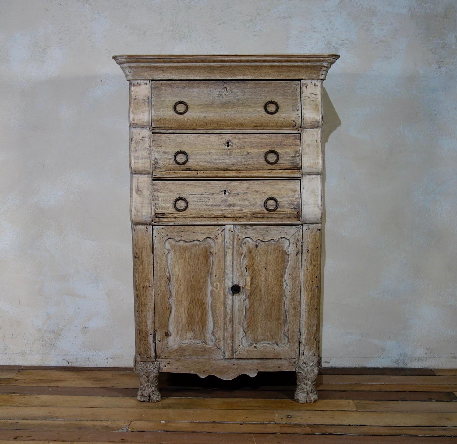 A unique 18th century bleached oak Dutch secretaire, featuring large circular handles to all three of the gradually shaped drawers above a double door cupboard. The top drawer displays a fold-down front, raised on carved claw-like feet demonstrating