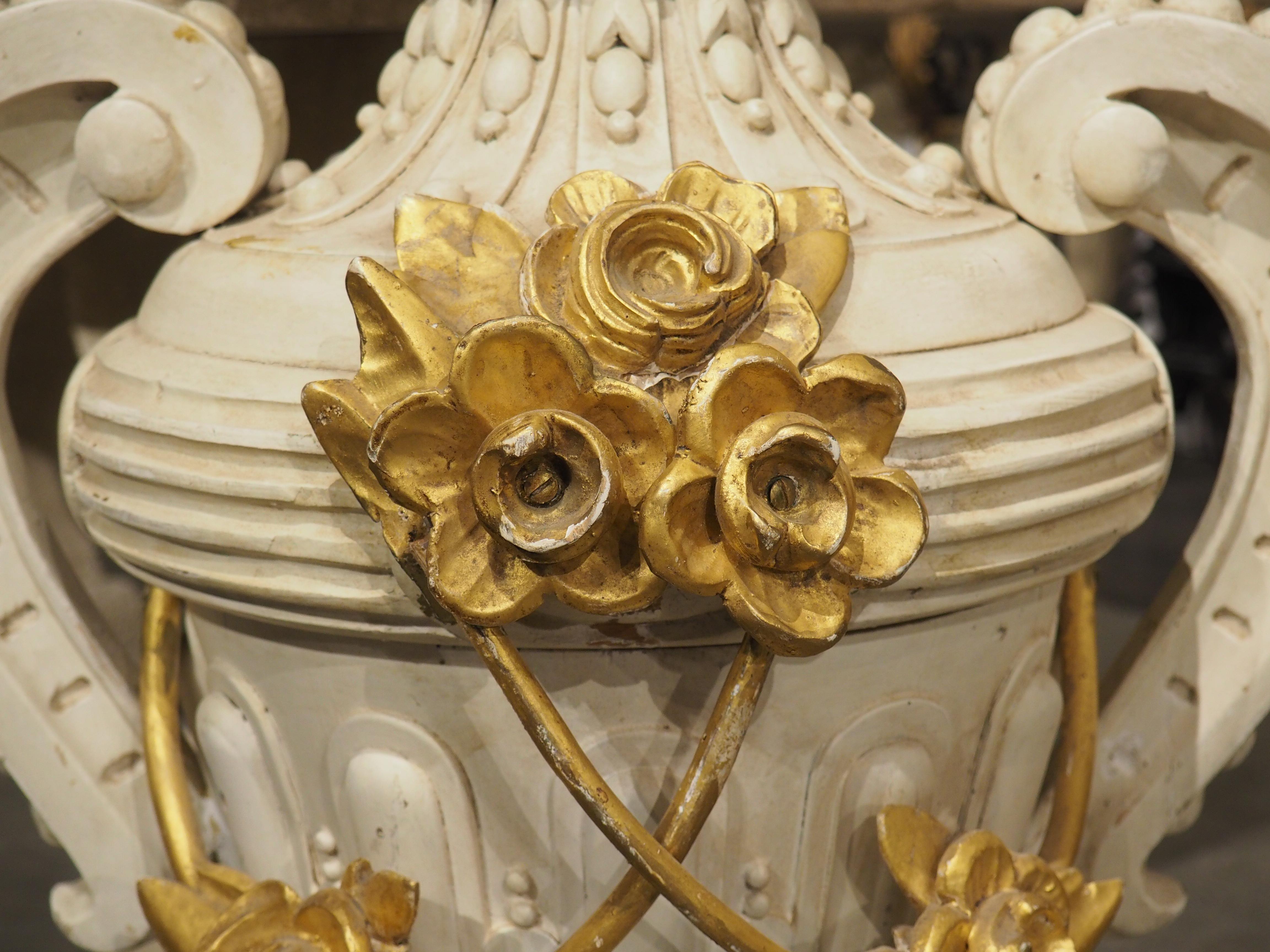 Hand-carved in Florence, Italy, in the 1800s, this tall wooden urn has been finished with a white lacquer and golden elements inspired by nature. A golden fruit bouquet arises from the top, above a neck adorned with beading and widely spaced fluting